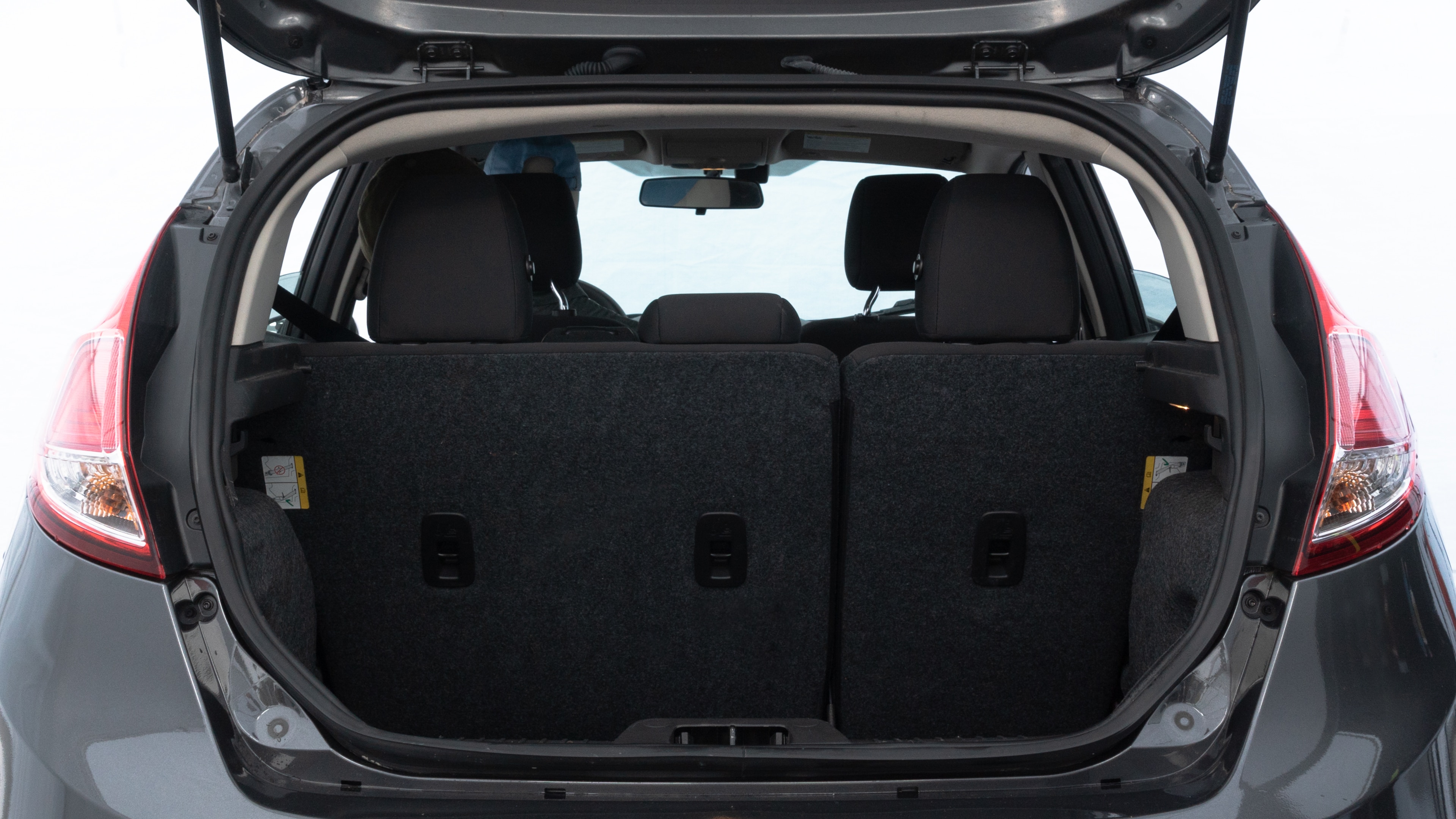 The trunk lid is open, showing full view of the trunk space. Two medium and one small suitcases are placed inside.