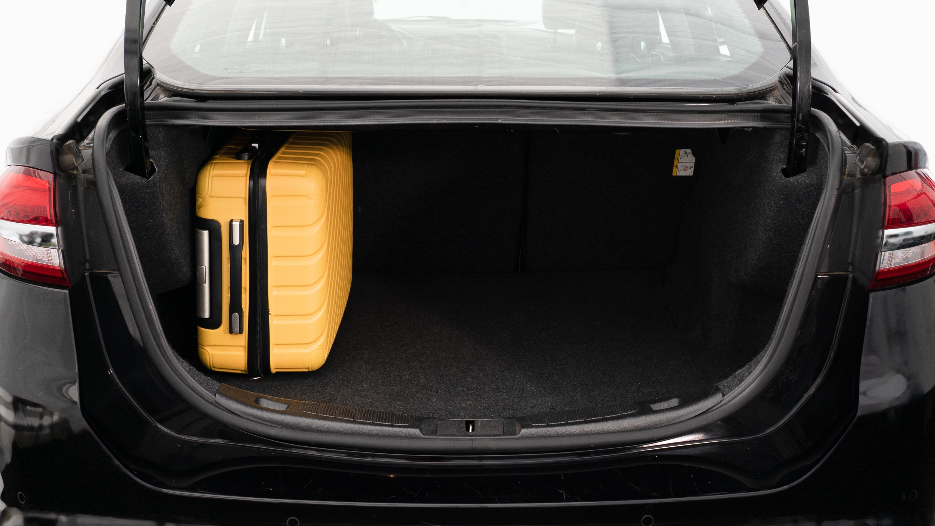 The trunk lid is open, showing a full view of the trunk space. Three large and two small suitcases are place inside