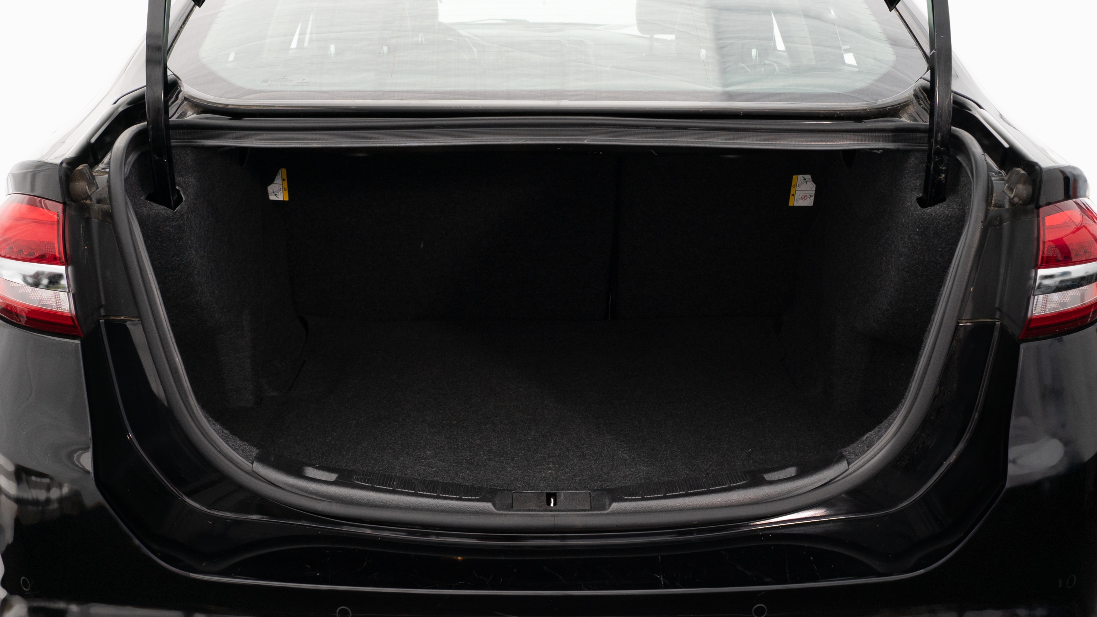 The trunk lid is open, showing a full view of the trunk space. Three large and two small suitcases are place inside