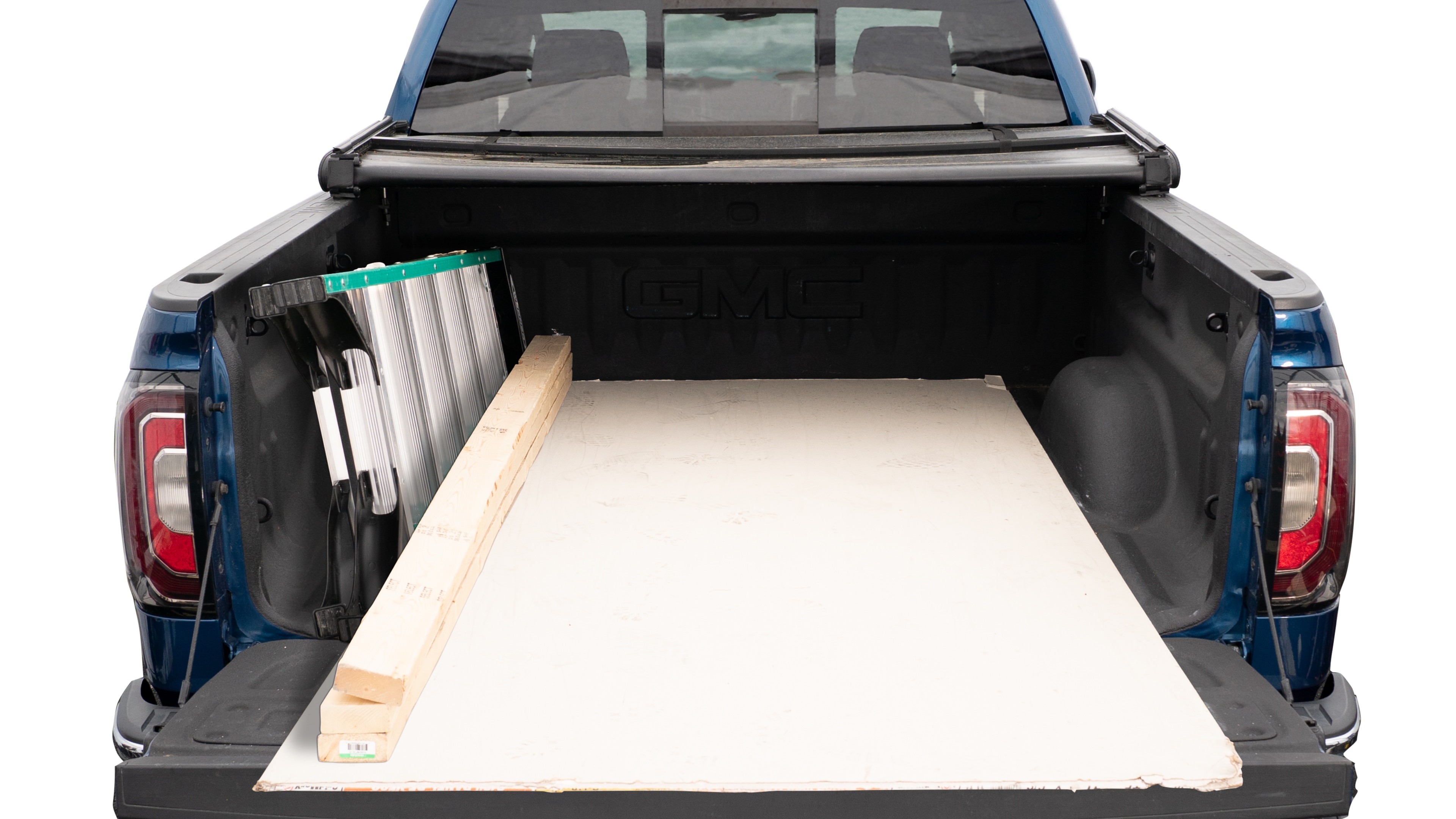 The trunk area is open giving a full view of the trunk area. A ladder, three 2 by 4 framing studs, two toolboxes and a 4 by 8 drywall sheet are placed inside.