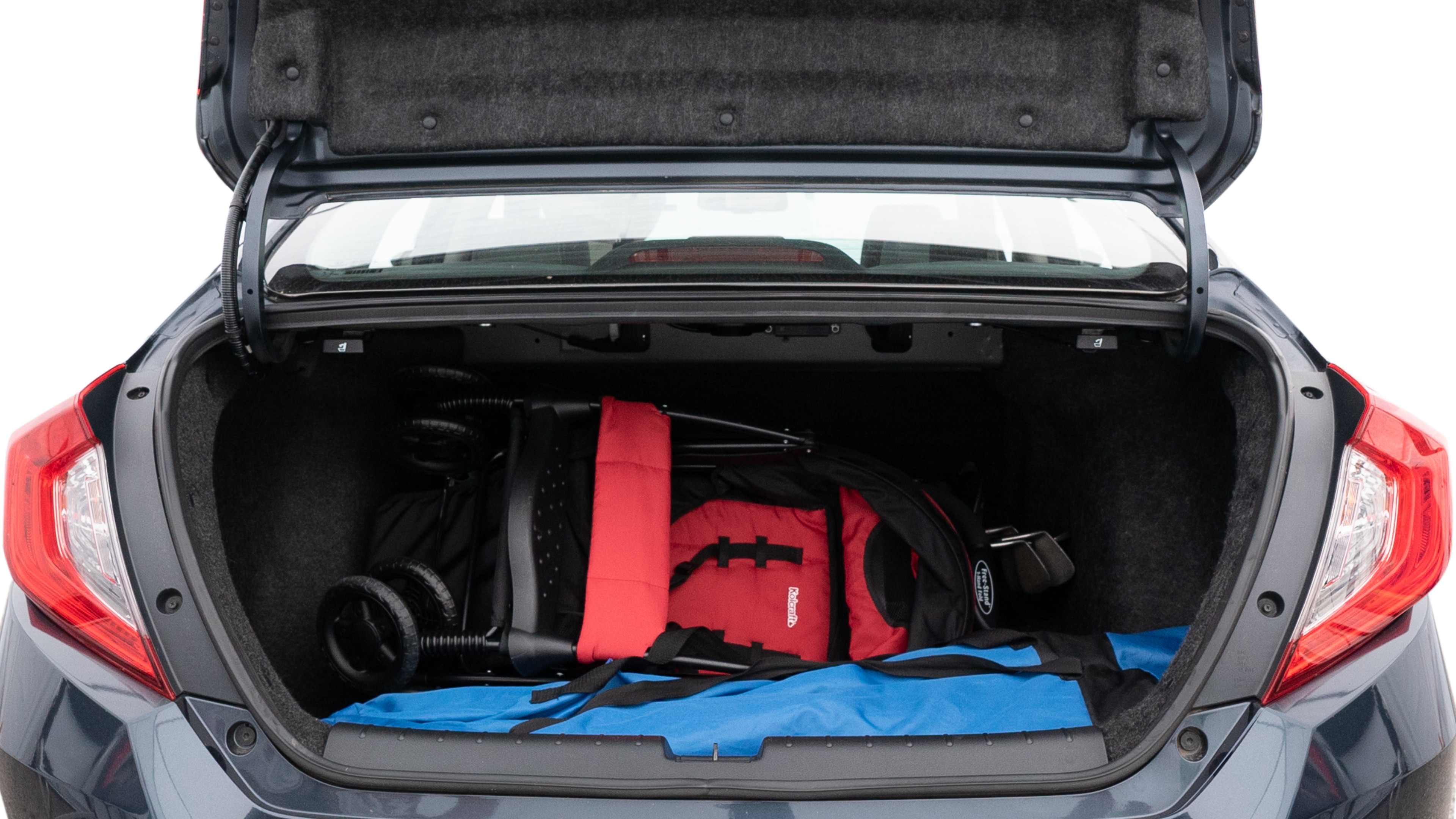 The trunk lid is open showing full view of the trunk. A baby stroller, three grocery carriers, two camping chairs in the carrying bag, and a set of golf clubs are placed inside.