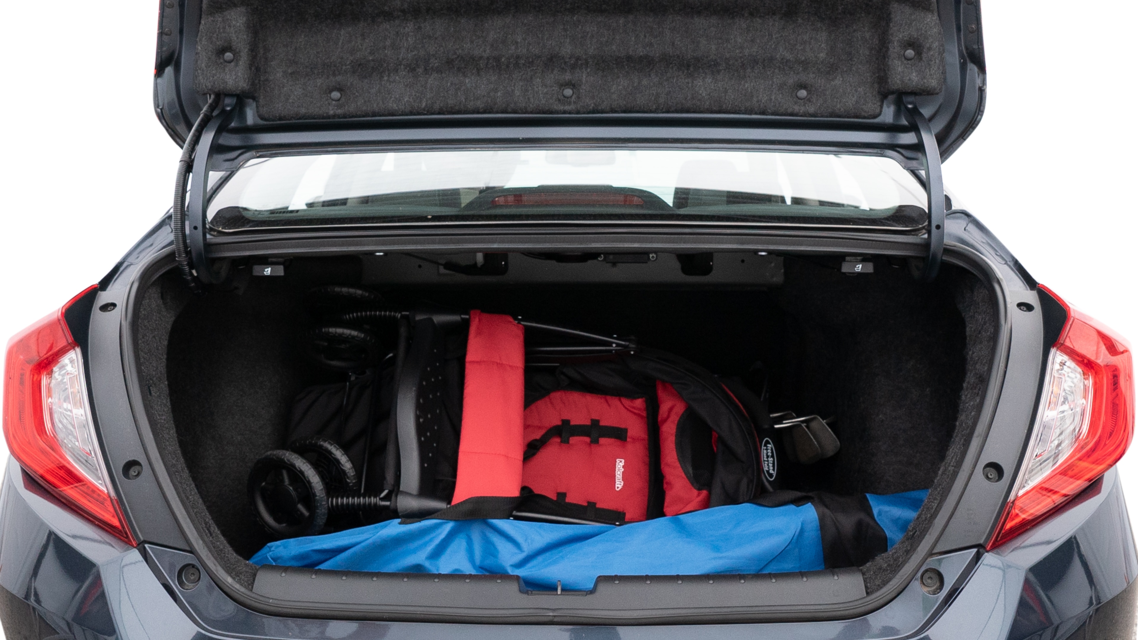 The trunk lid is open showing full view of the trunk. A baby stroller, three grocery carriers, two camping chairs in the carrying bag, and a set of golf clubs are placed inside.