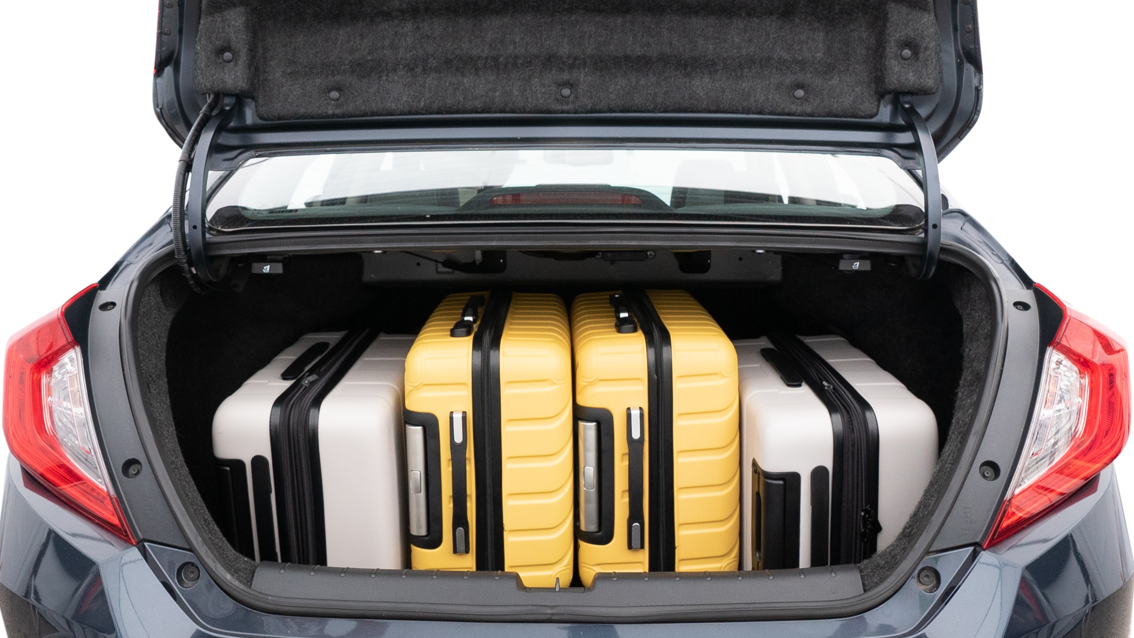 The trunk lid is open, showing full view of the trunk space. Two medium and two small suitcases are placed inside.
