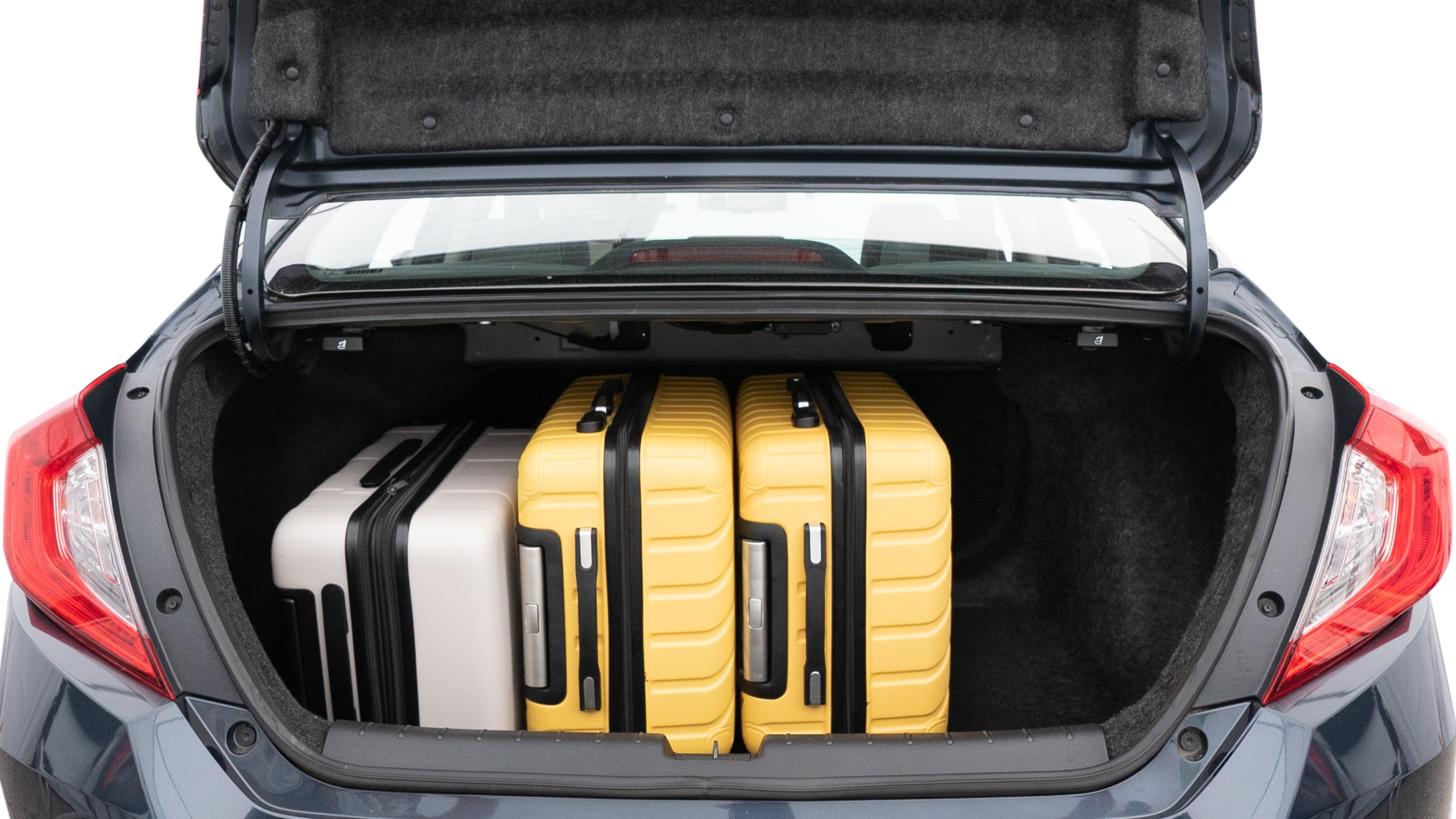 The trunk lid is open, showing full view of the trunk space. Two medium and two small suitcases are placed inside.