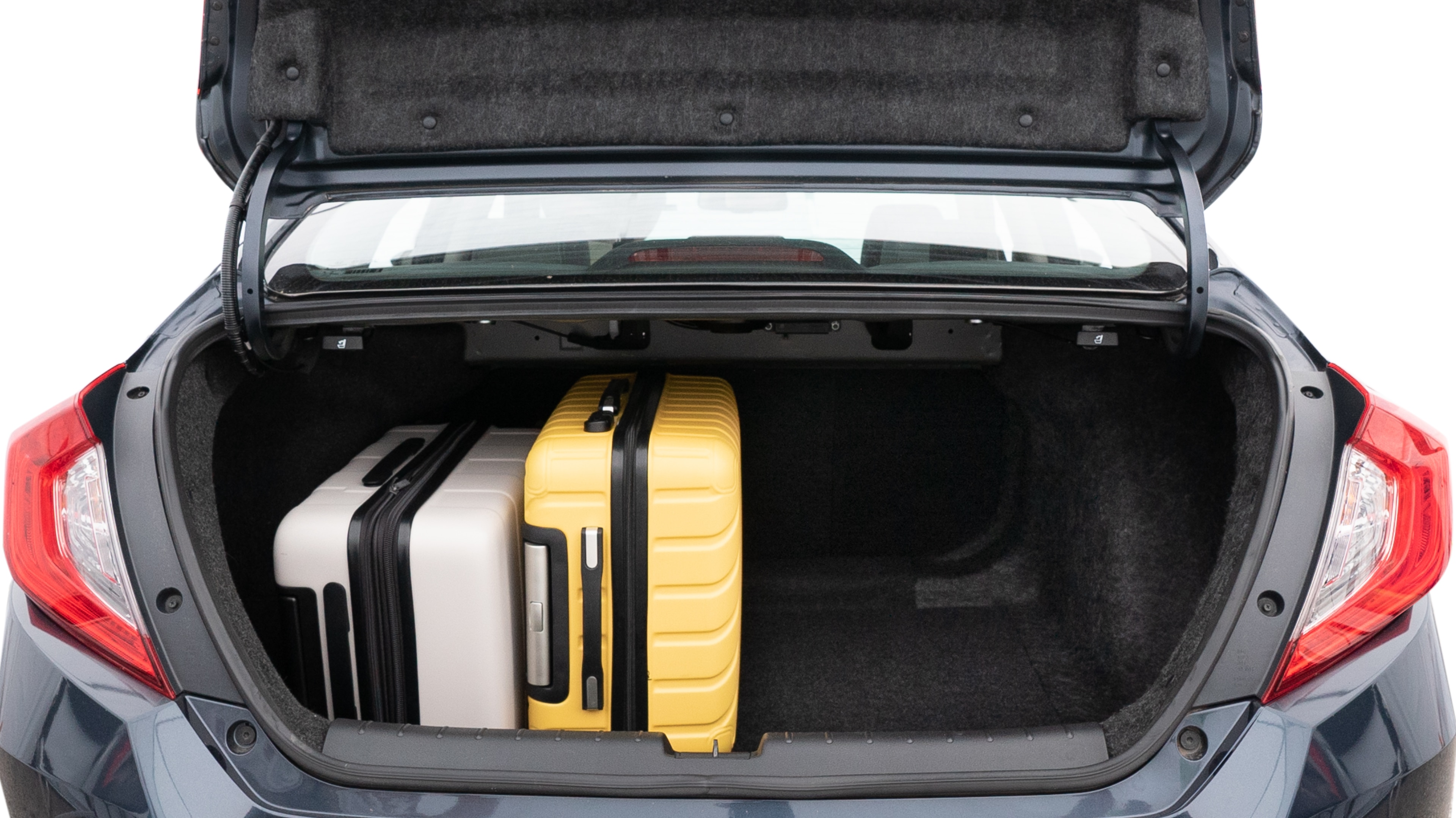 The trunk lid is open, showing full view of the trunk space. Two medium and two small suitcases are placed inside.