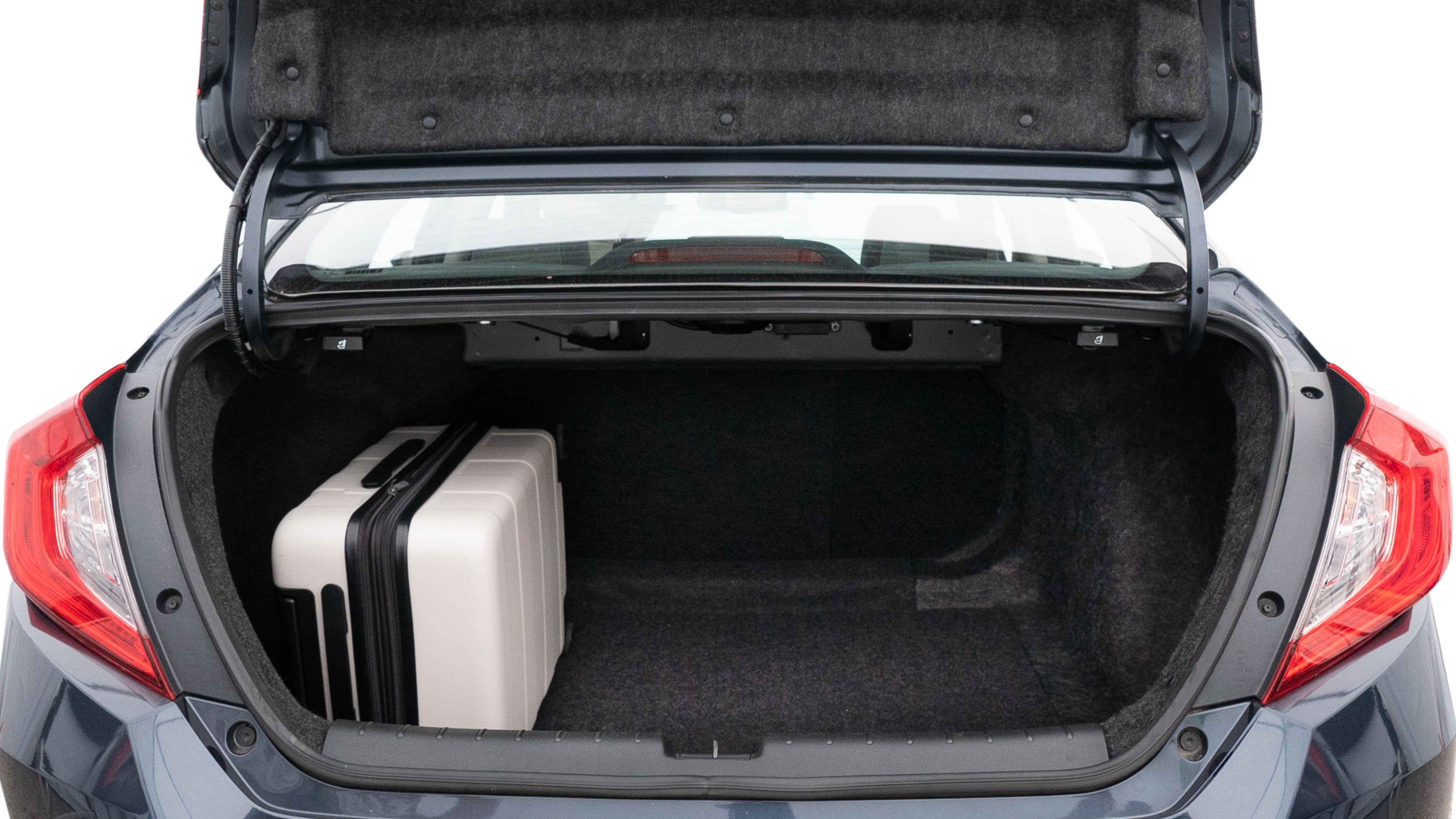 The trunk lid is open, showing full view of the trunk space. Two medium and two small suitcases are placed inside.
