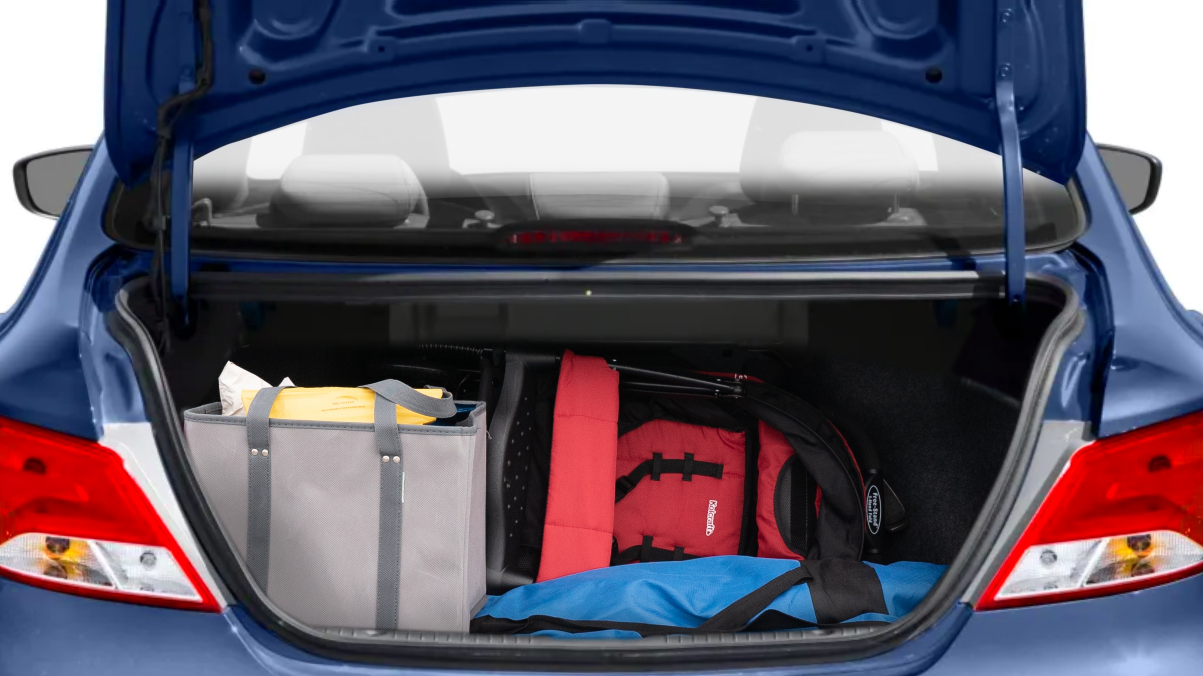 The trunk lid is open showing full view of the trunk. A baby stroller, three grocery carriers, two camping chairs in the carrying bag, and a set of golf clubs are placed inside.