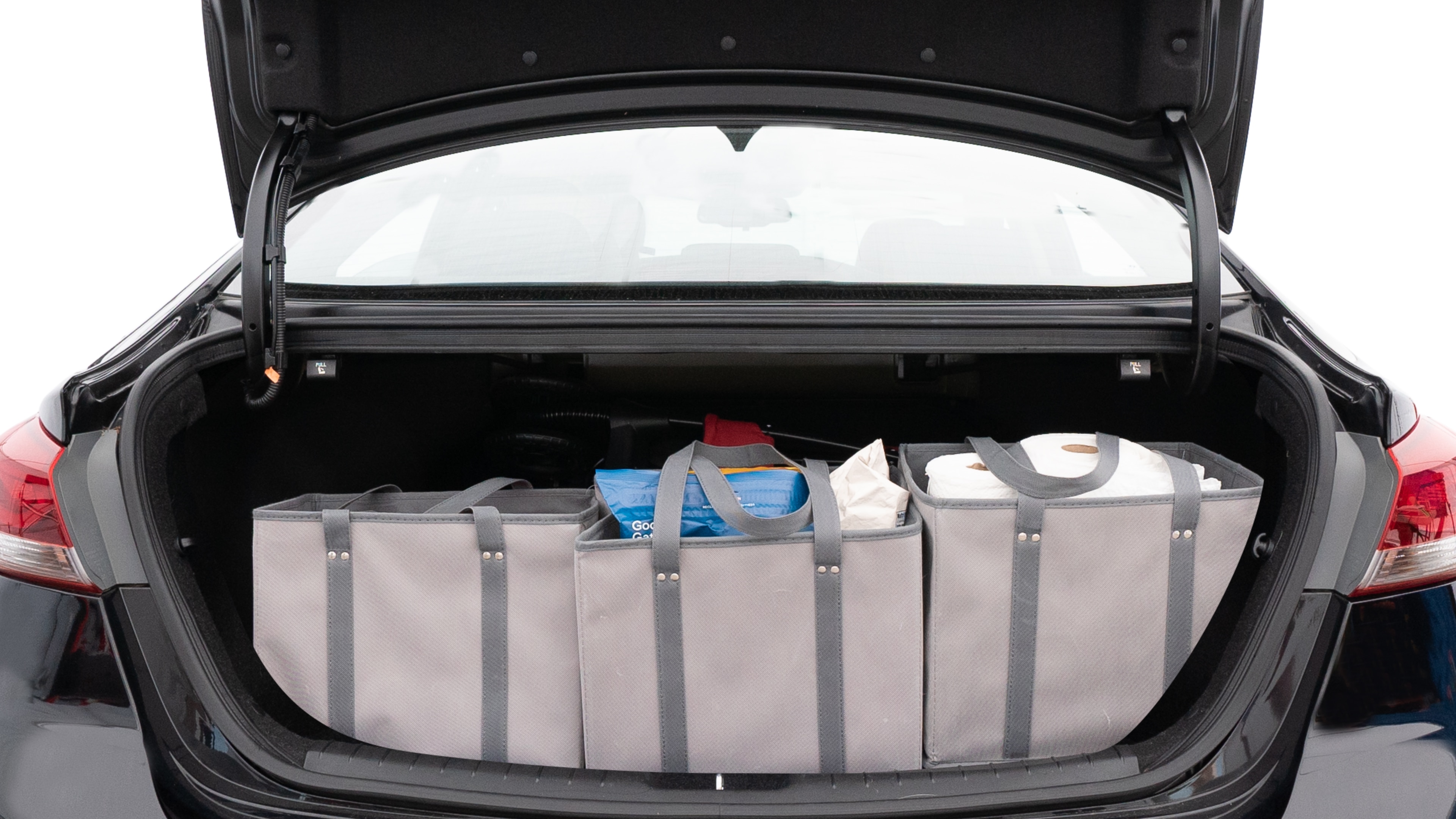 The trunk lid is open showing full view of the trunk. A baby stroller, three grocery carriers, two camping chairs in the carrying bag, and a set of golf clubs are placed inside.