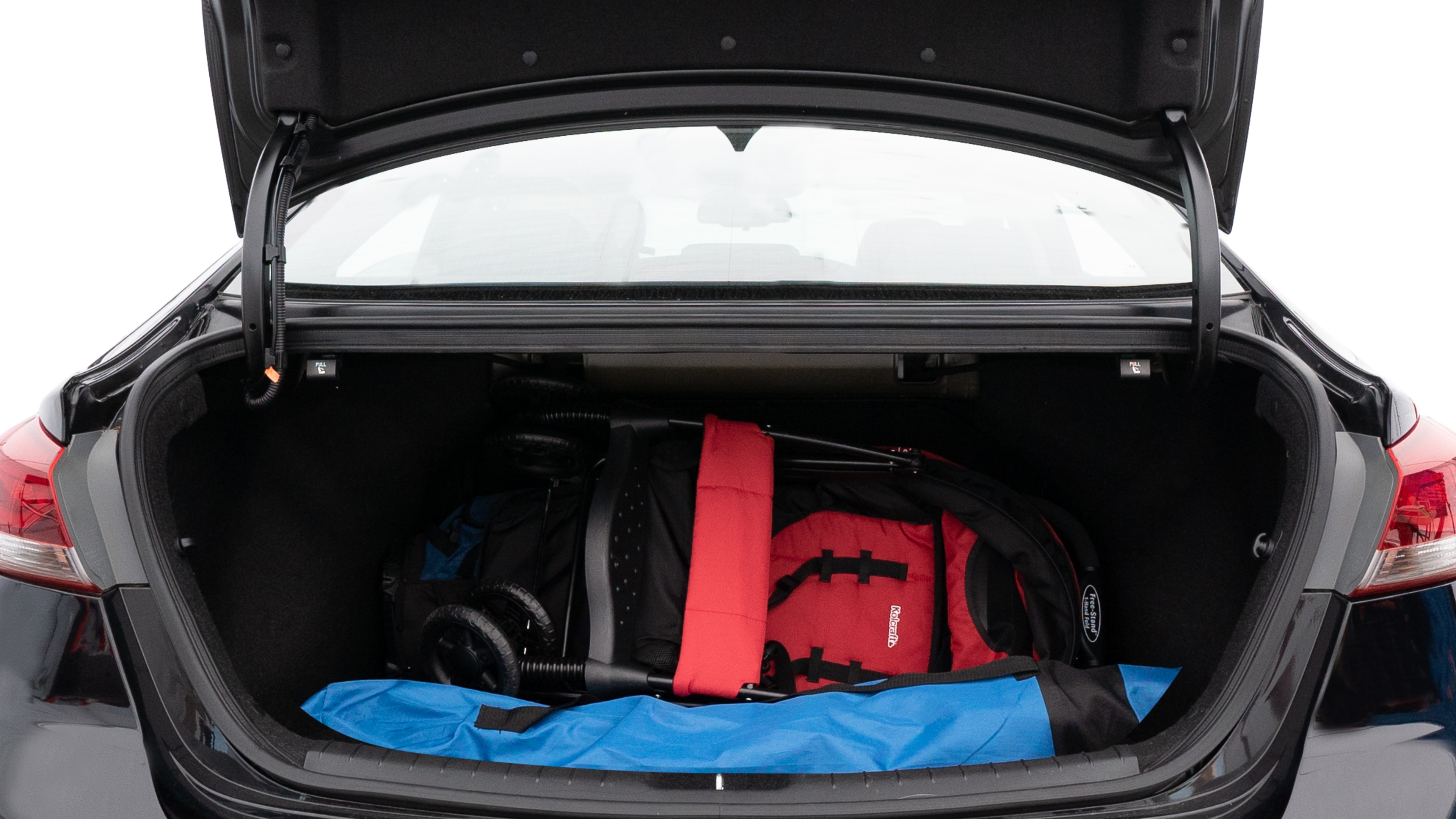 The trunk lid is open showing full view of the trunk. A baby stroller, three grocery carriers, two camping chairs in the carrying bag, and a set of golf clubs are placed inside.