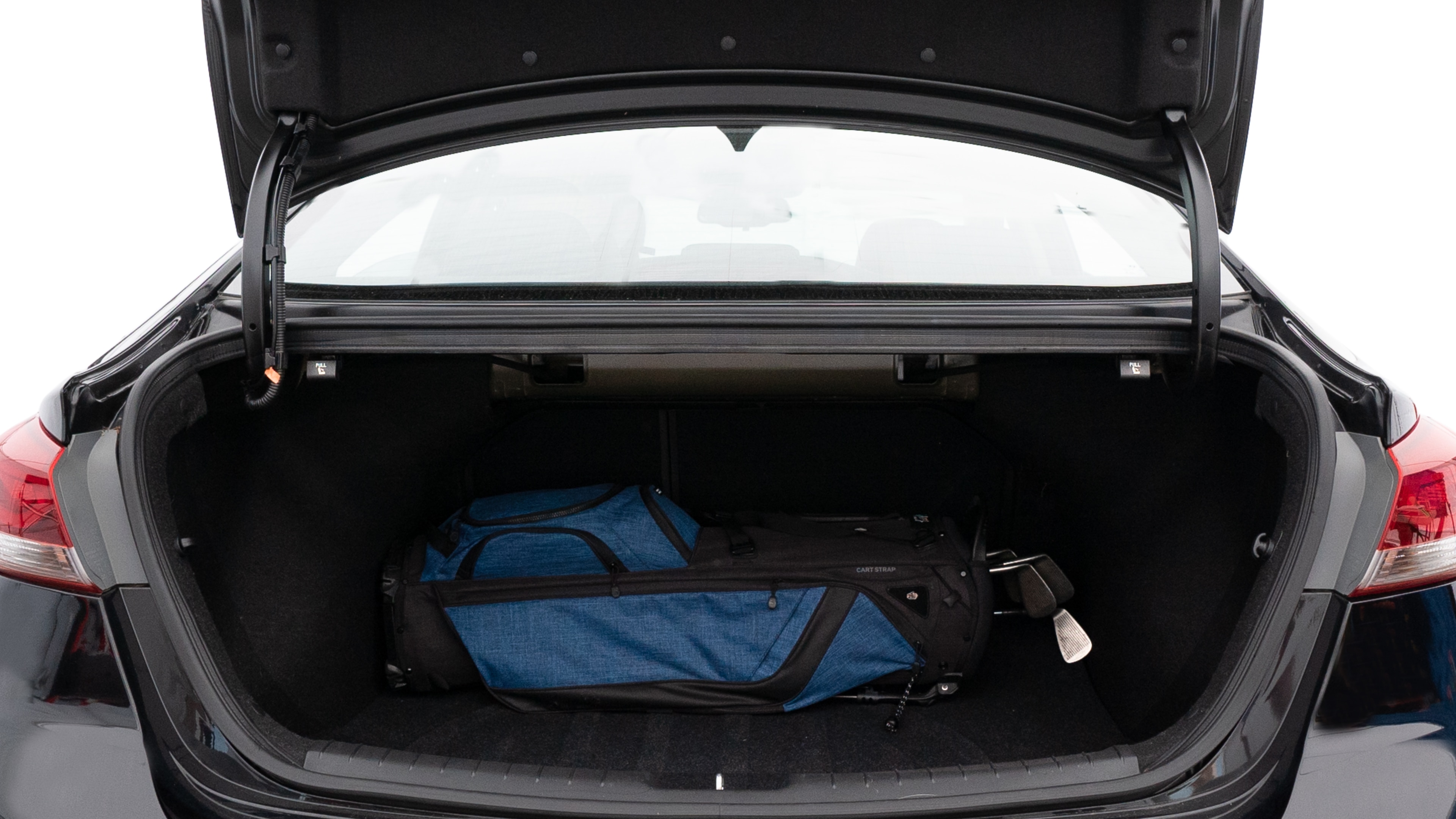 The trunk lid is open showing full view of the trunk. A baby stroller, three grocery carriers, two camping chairs in the carrying bag, and a set of golf clubs are placed inside.