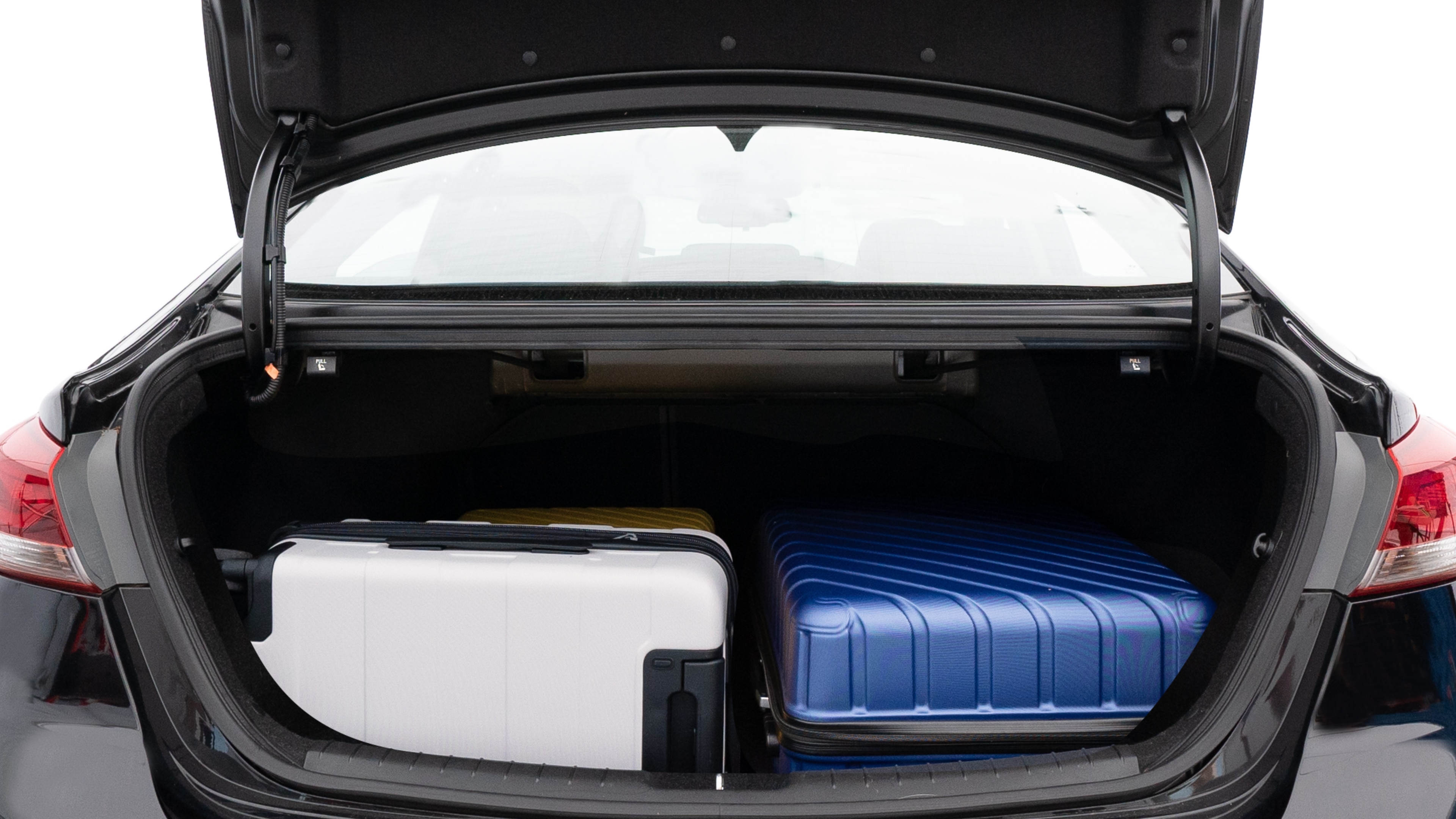 The trunk lid is open, showing full view of the trunk space. One large, one medium, and one small suitcases are placed inside.