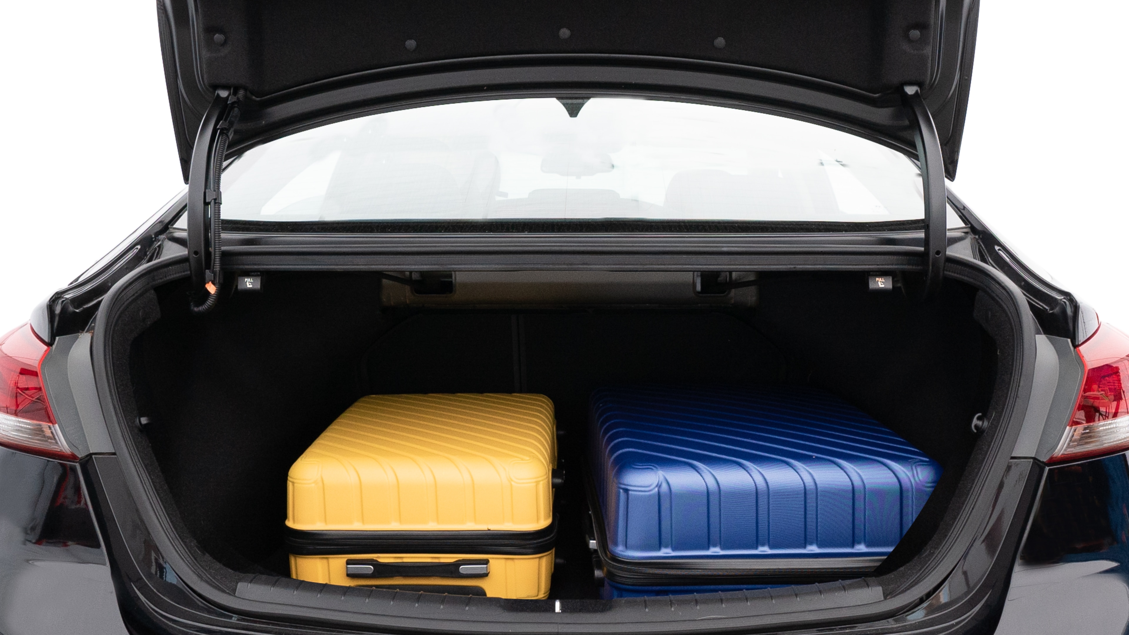 The trunk lid is open, showing full view of the trunk space. One large, one medium, and one small suitcases are placed inside.