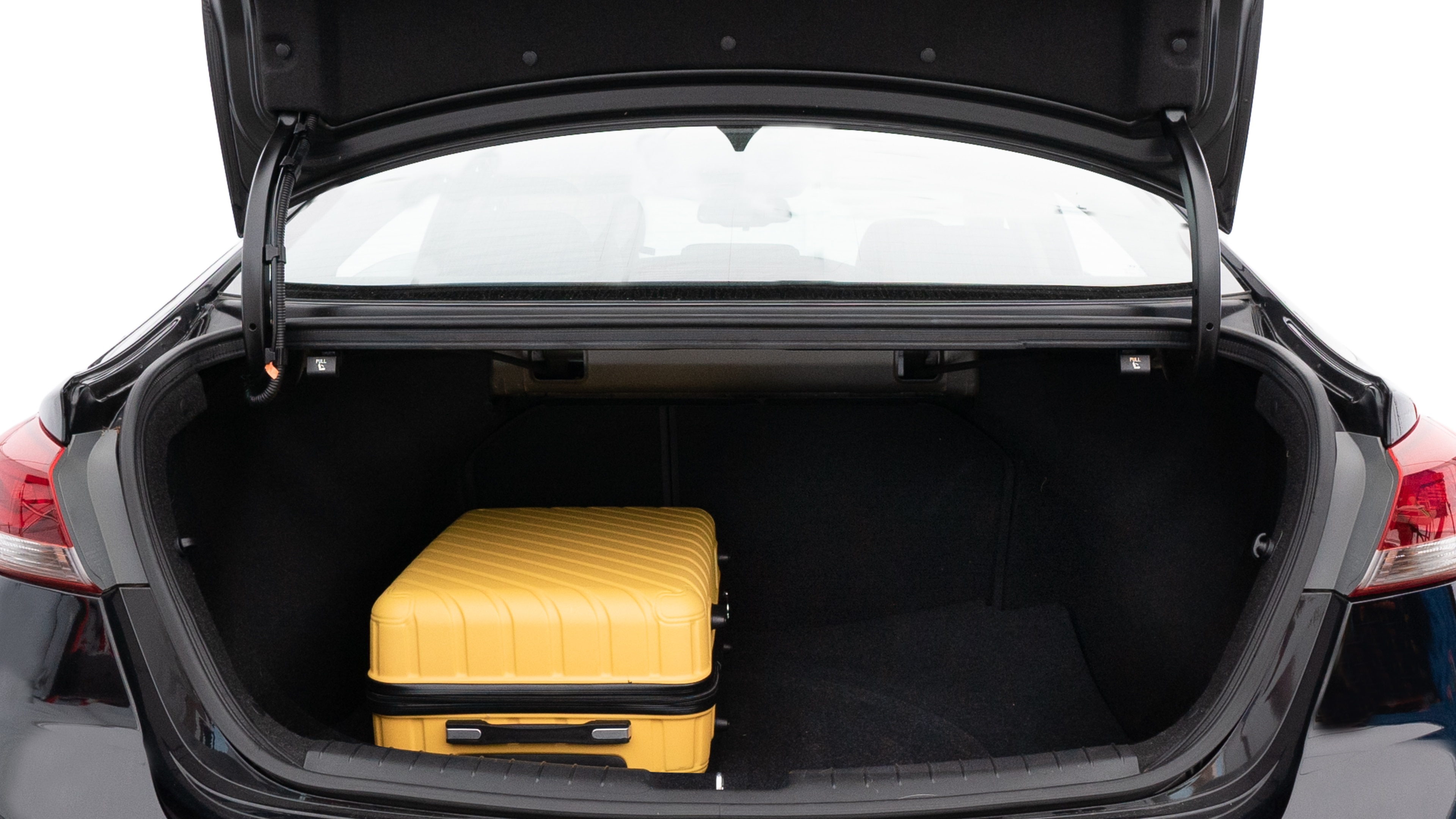 The trunk lid is open, showing full view of the trunk space. One large, one medium, and one small suitcases are placed inside.