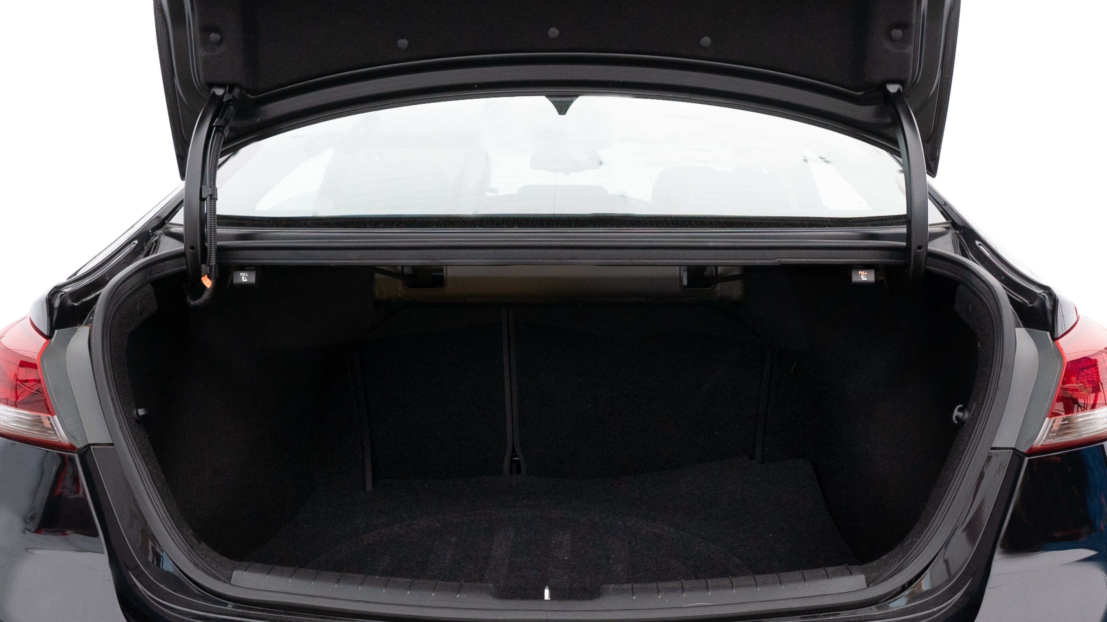 The trunk lid is open, showing full view of the trunk space. One large, one medium, and one small suitcases are placed inside.