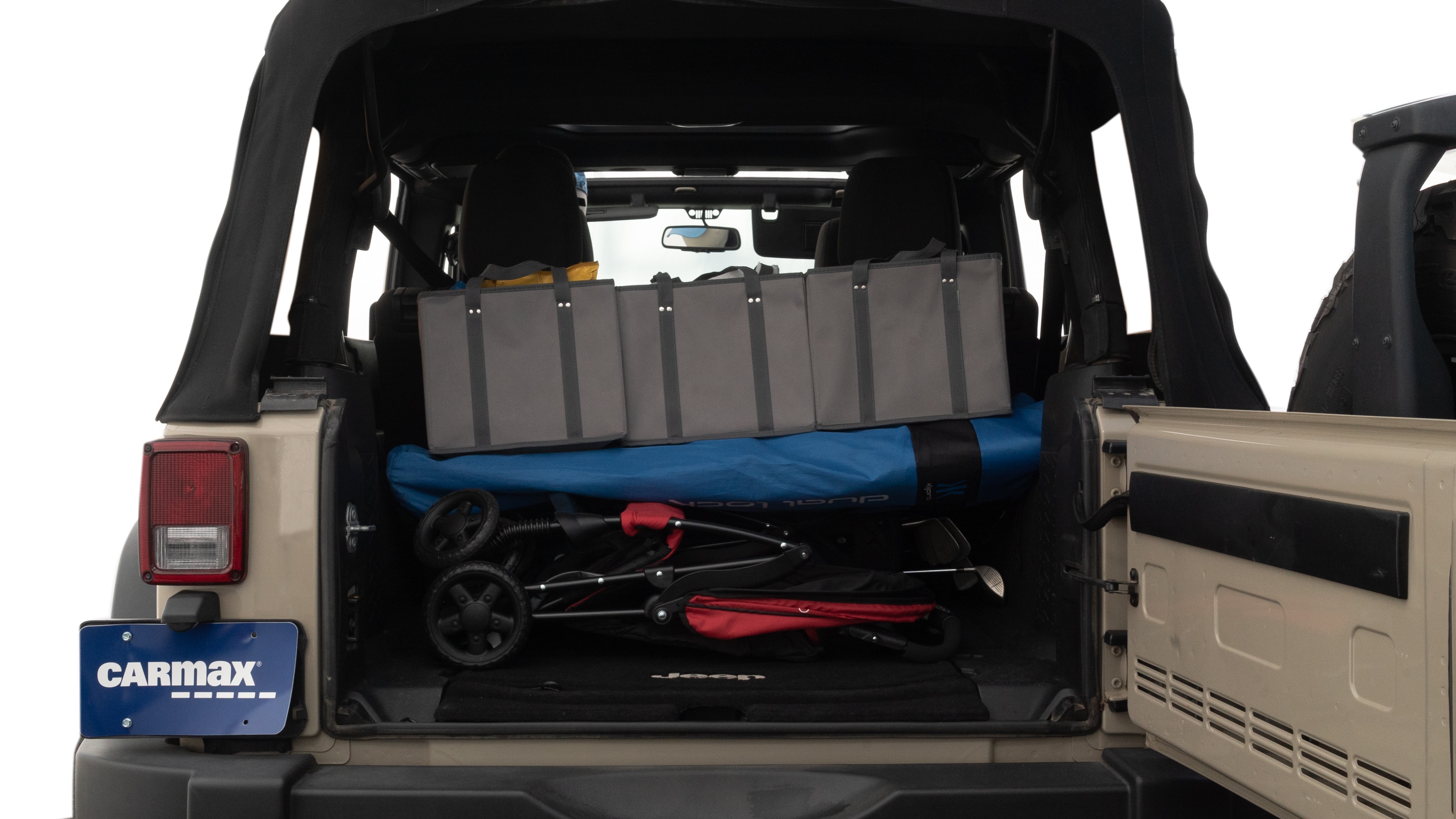 The trunk lid is open showing full view of the trunk. A baby stroller, three grocery carriers, two camping chairs in the carrying bag, and a set of golf clubs are placed inside.