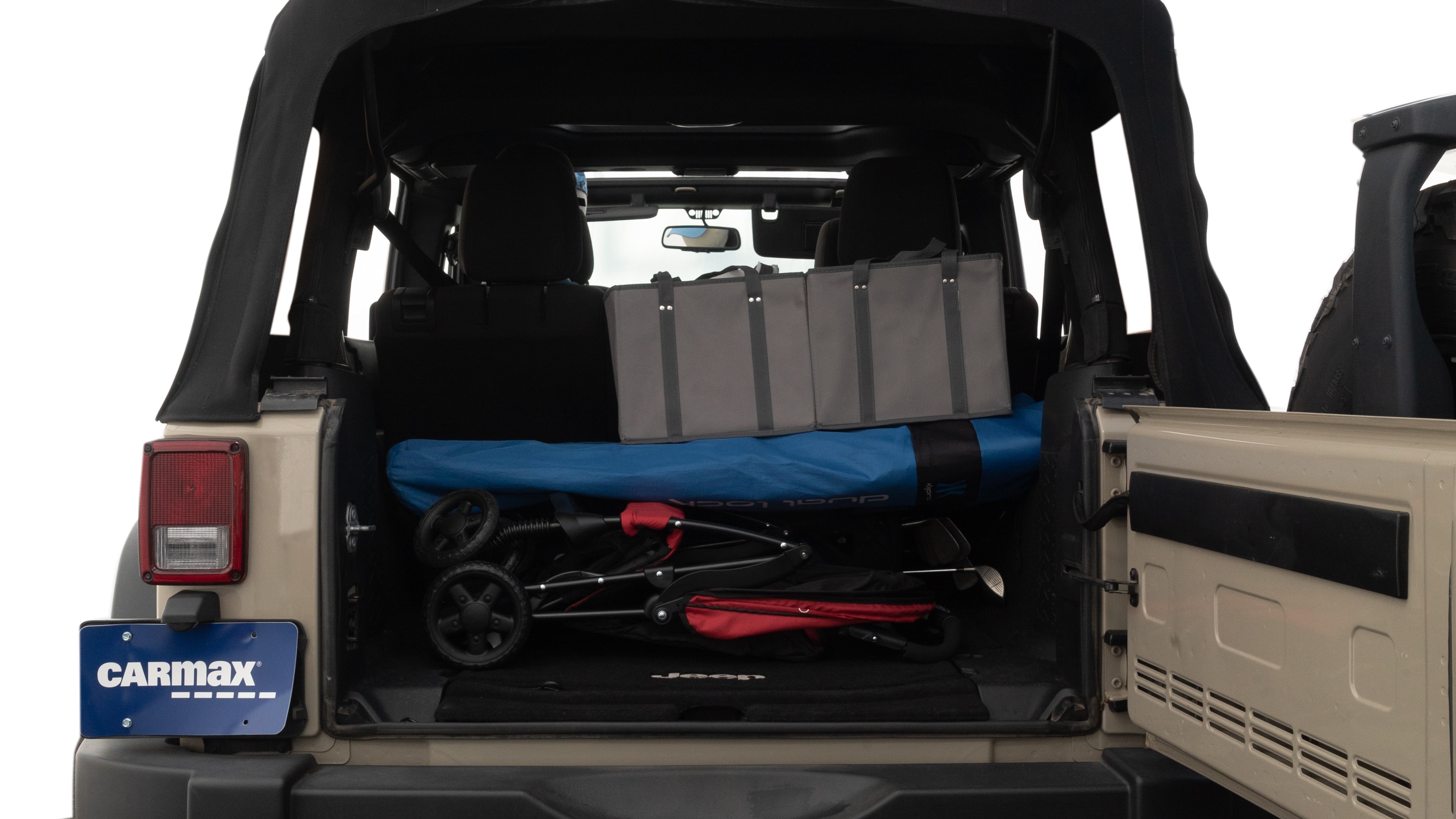 The trunk lid is open showing full view of the trunk. A baby stroller, three grocery carriers, two camping chairs in the carrying bag, and a set of golf clubs are placed inside.