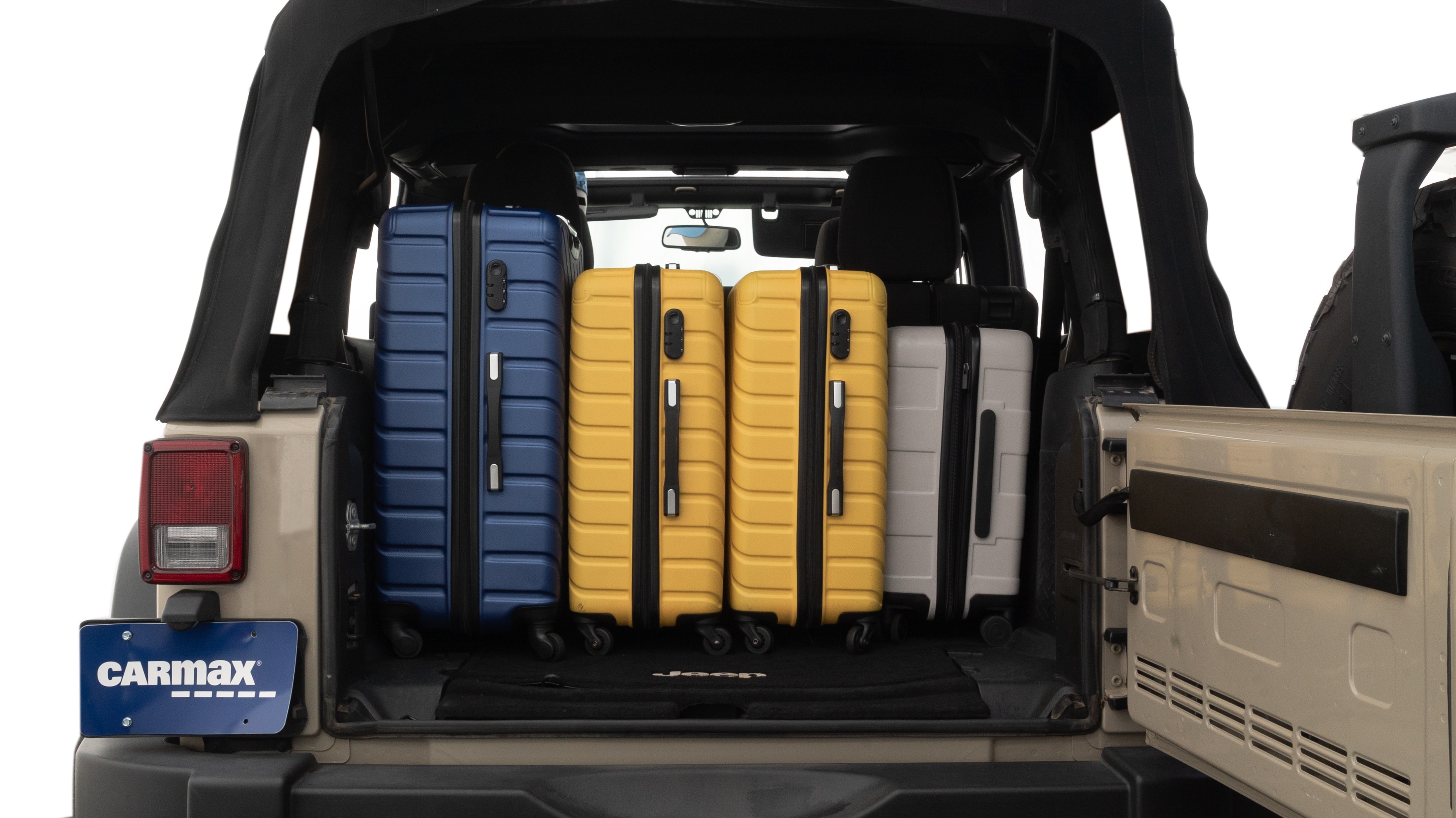 The trunk lid is open, showing full view of the trunk space. One large, two medium, and one small suitcases are placed inside.