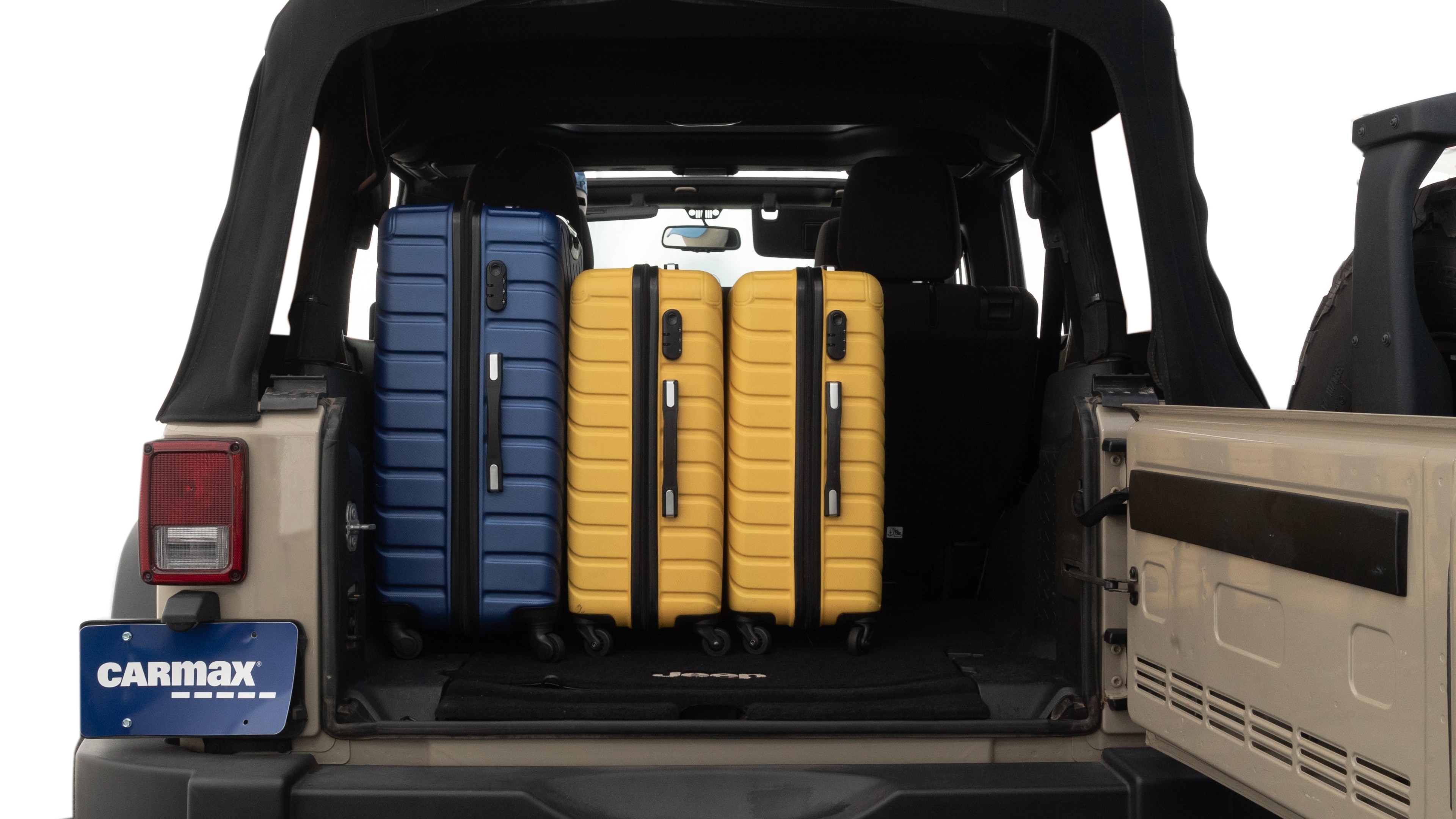 The trunk lid is open, showing full view of the trunk space. One large, two medium, and one small suitcases are placed inside.