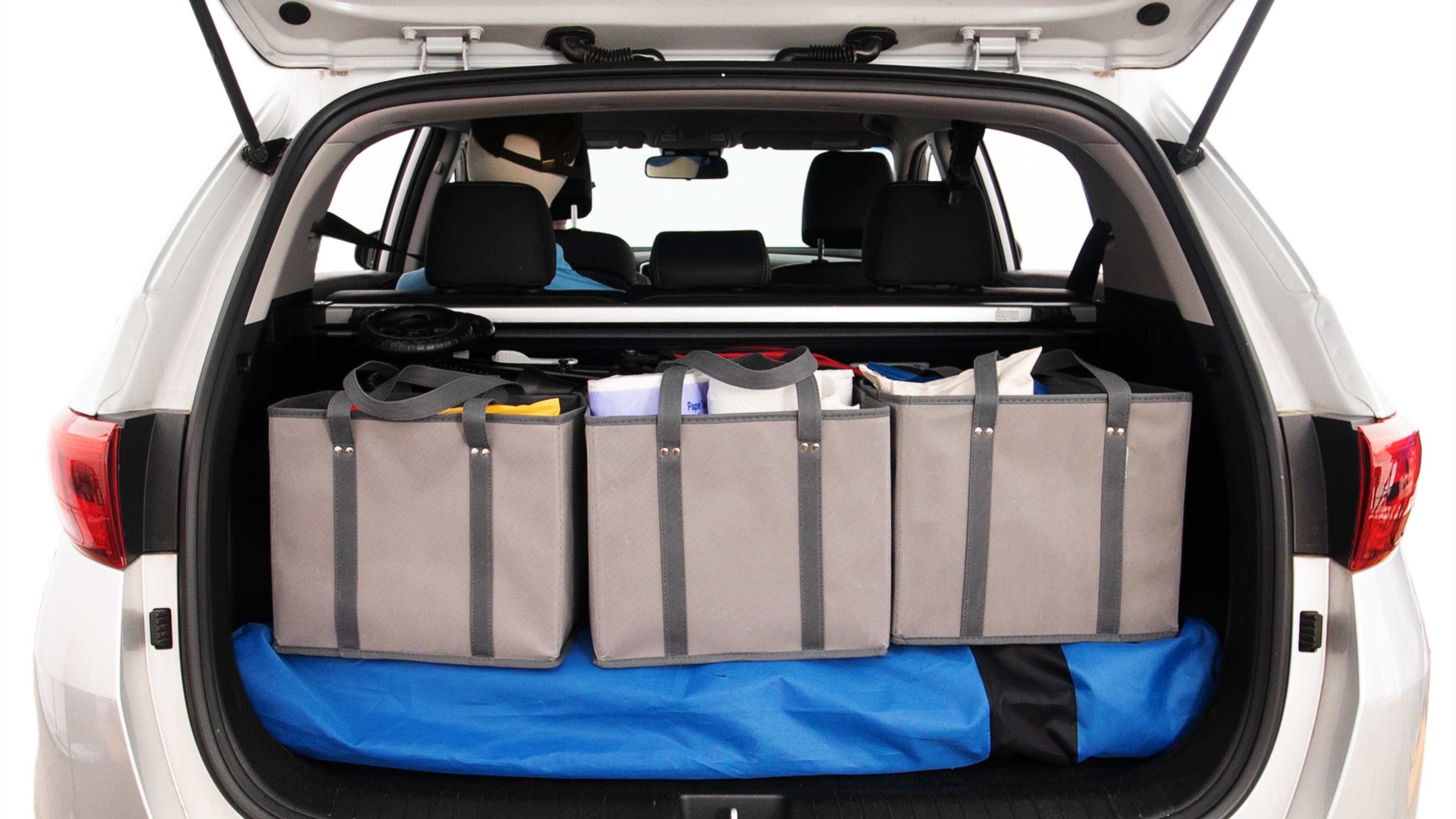 The trunk lid is open showing full view of the trunk. A baby stroller, three grocery carriers, two camping chairs in the carrying bag, and a set of golf clubs are placed inside.