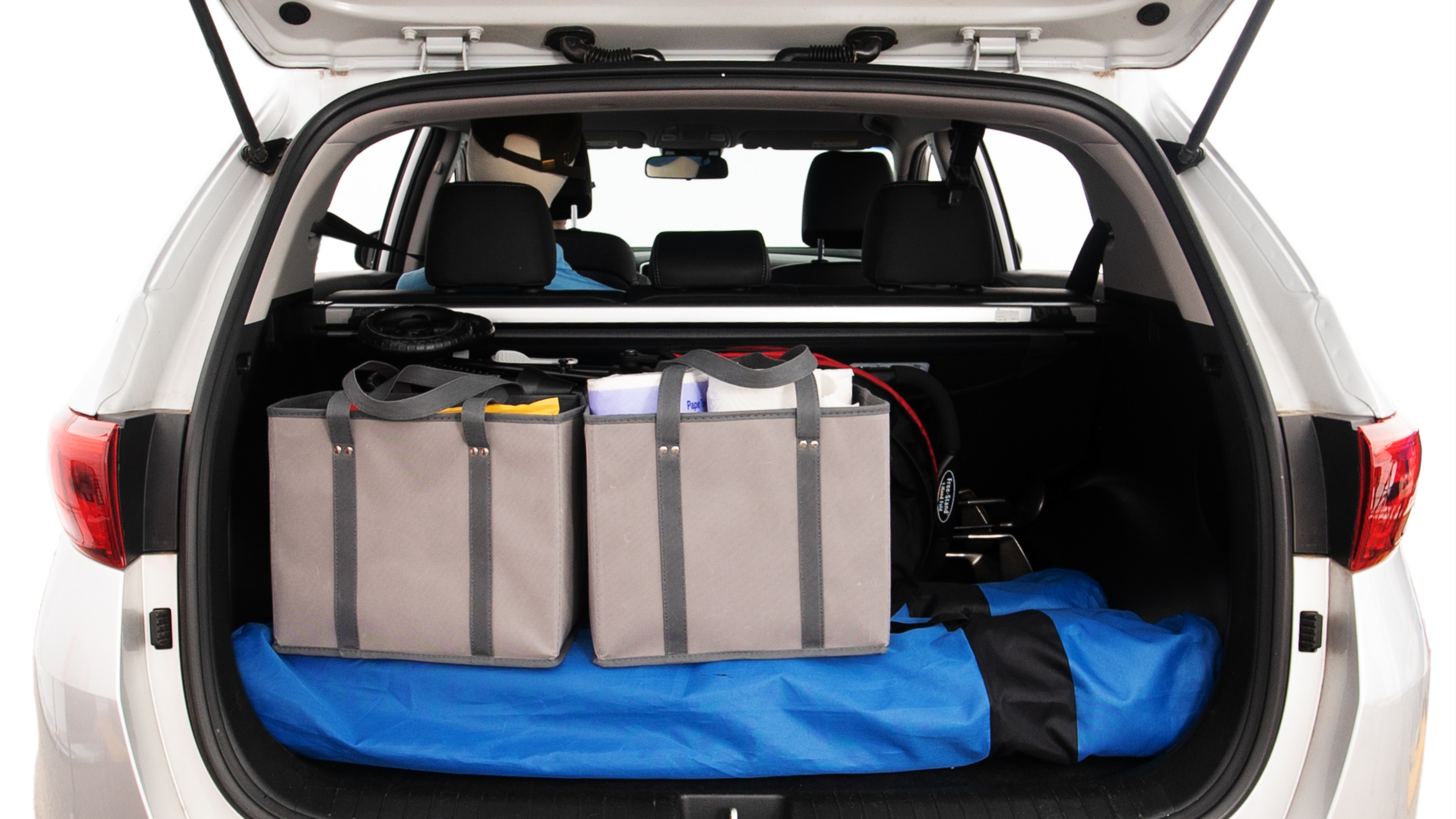 The trunk lid is open showing full view of the trunk. A baby stroller, three grocery carriers, two camping chairs in the carrying bag, and a set of golf clubs are placed inside.