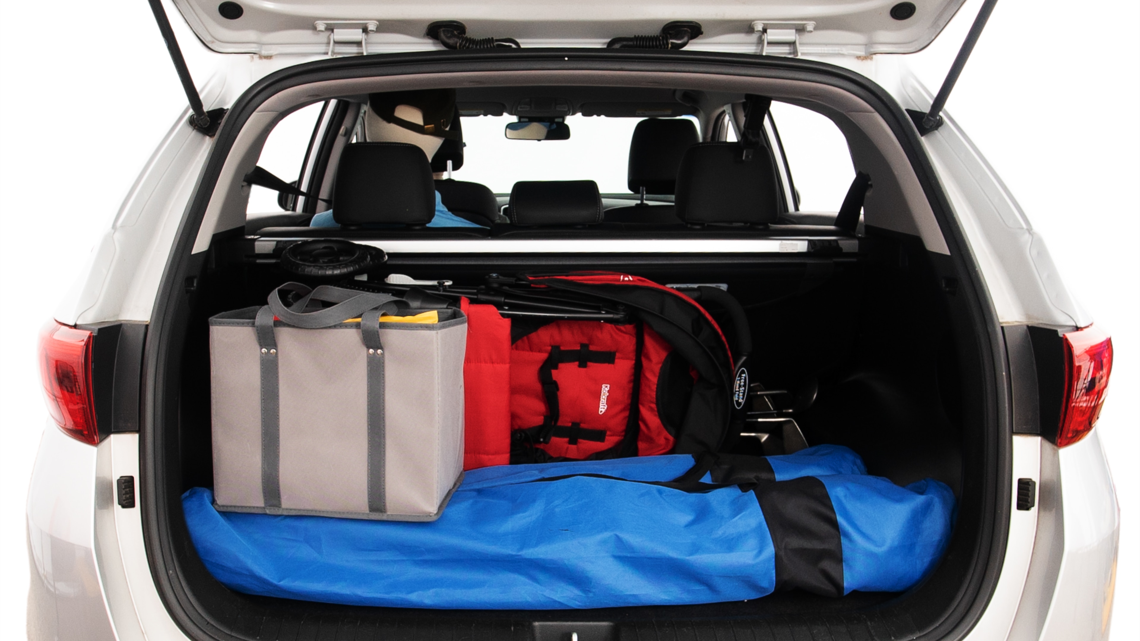 The trunk lid is open showing full view of the trunk. A baby stroller, three grocery carriers, two camping chairs in the carrying bag, and a set of golf clubs are placed inside.
