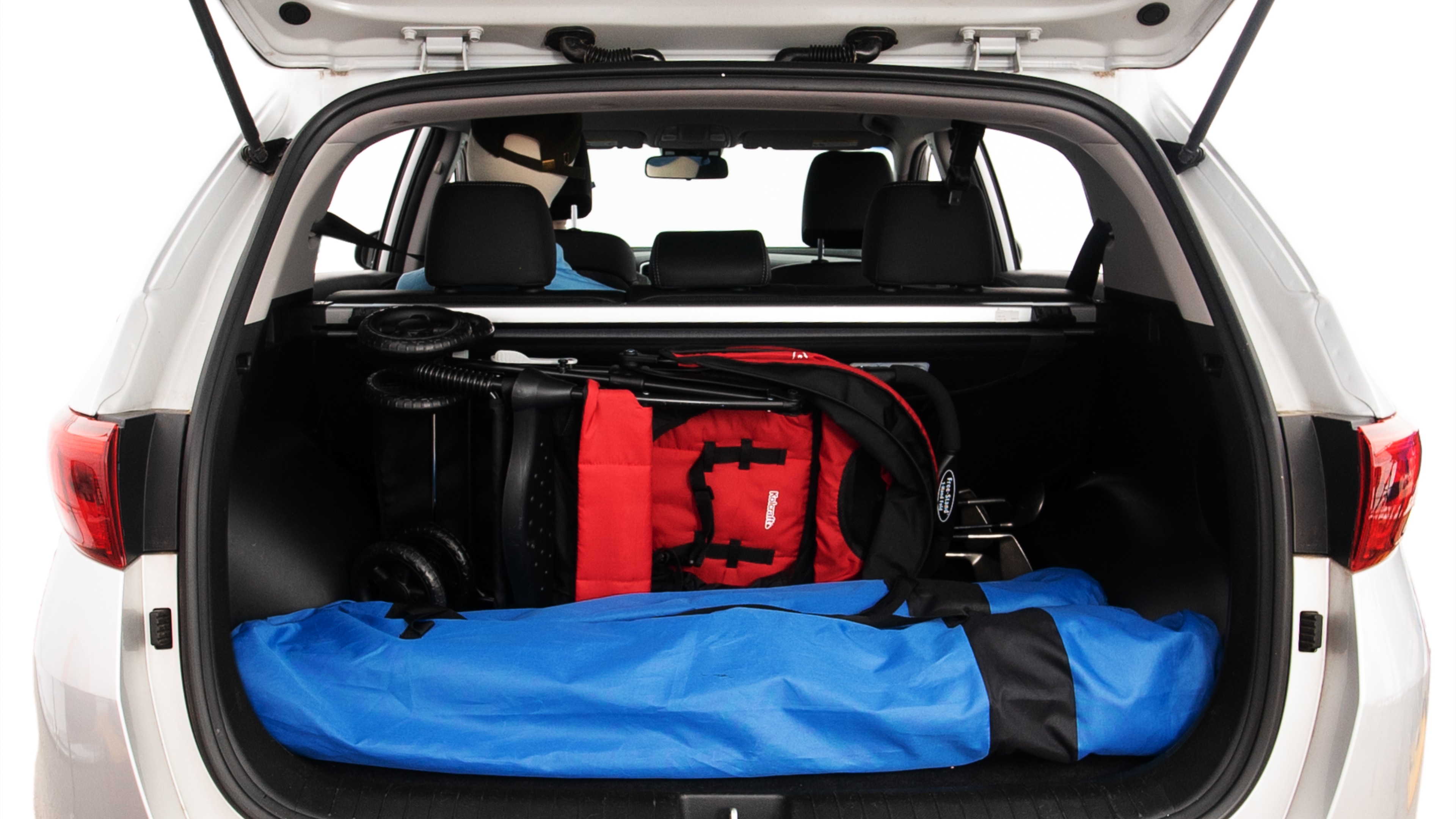 The trunk lid is open showing full view of the trunk. A baby stroller, three grocery carriers, two camping chairs in the carrying bag, and a set of golf clubs are placed inside.