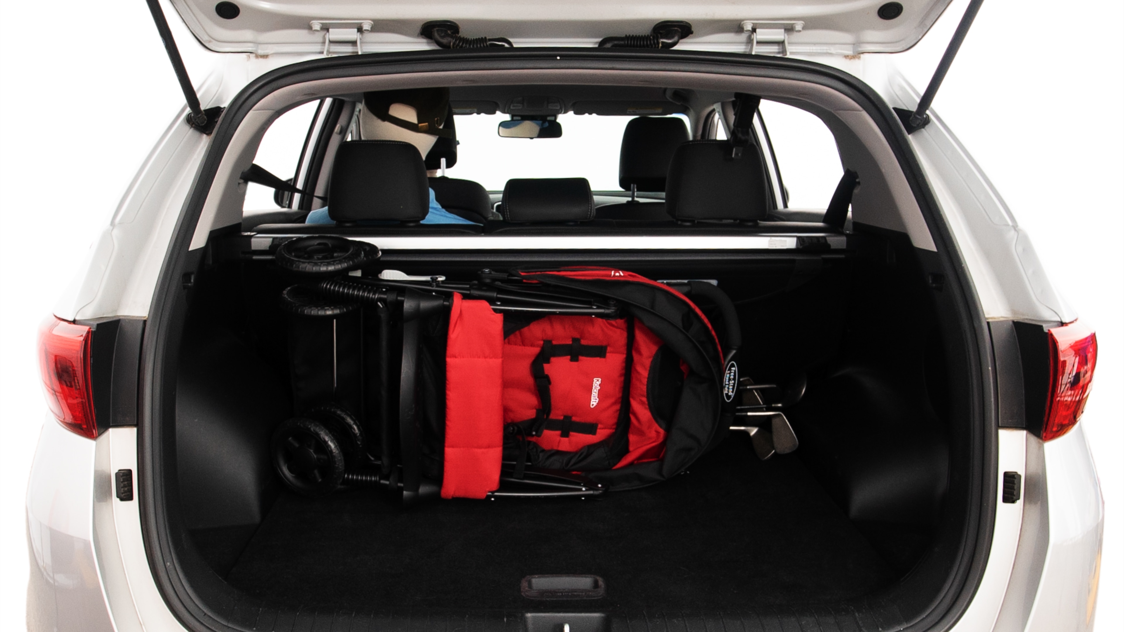 The trunk lid is open showing full view of the trunk. A baby stroller, three grocery carriers, two camping chairs in the carrying bag, and a set of golf clubs are placed inside.