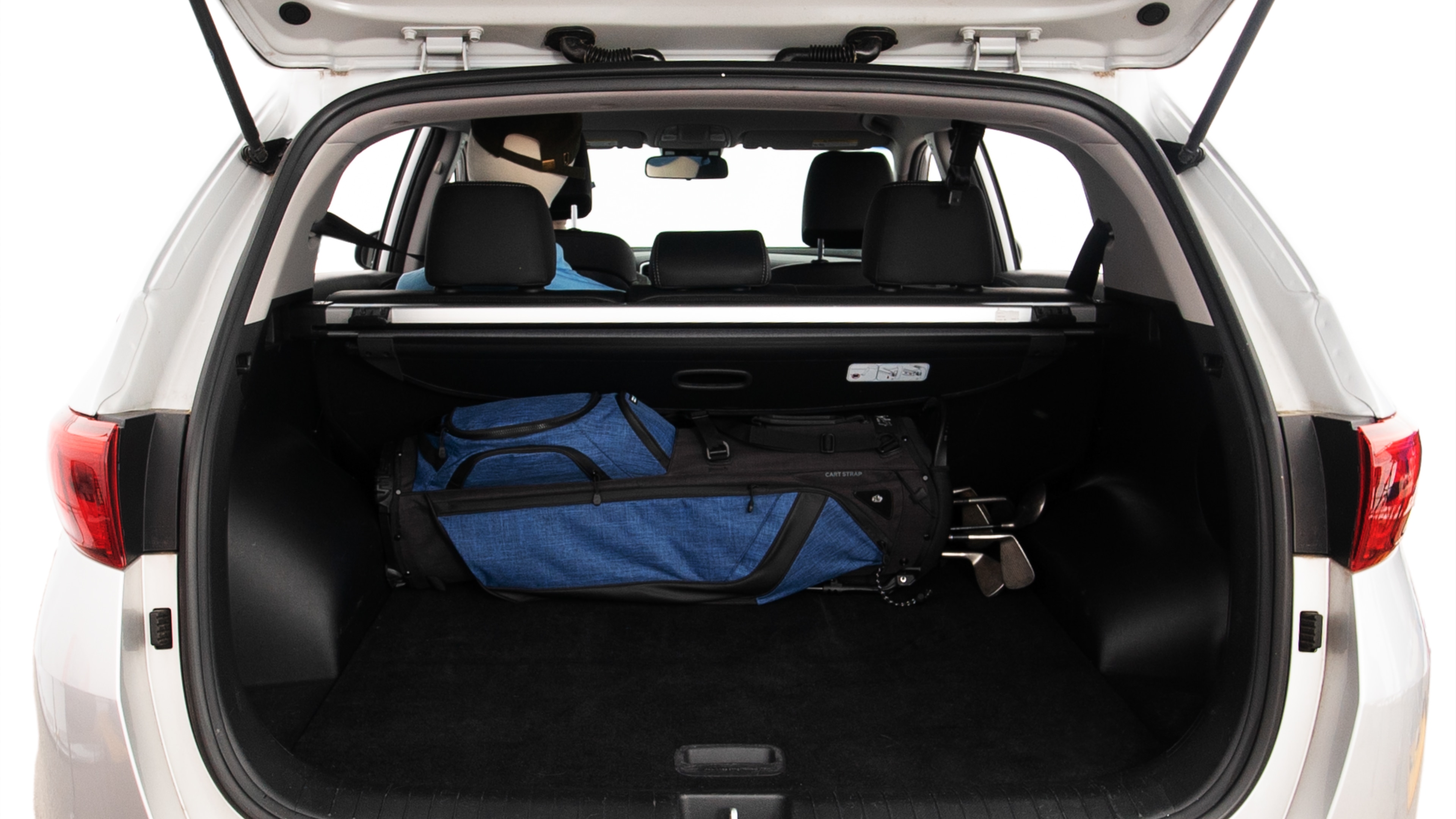 The trunk lid is open showing full view of the trunk. A baby stroller, three grocery carriers, two camping chairs in the carrying bag, and a set of golf clubs are placed inside.