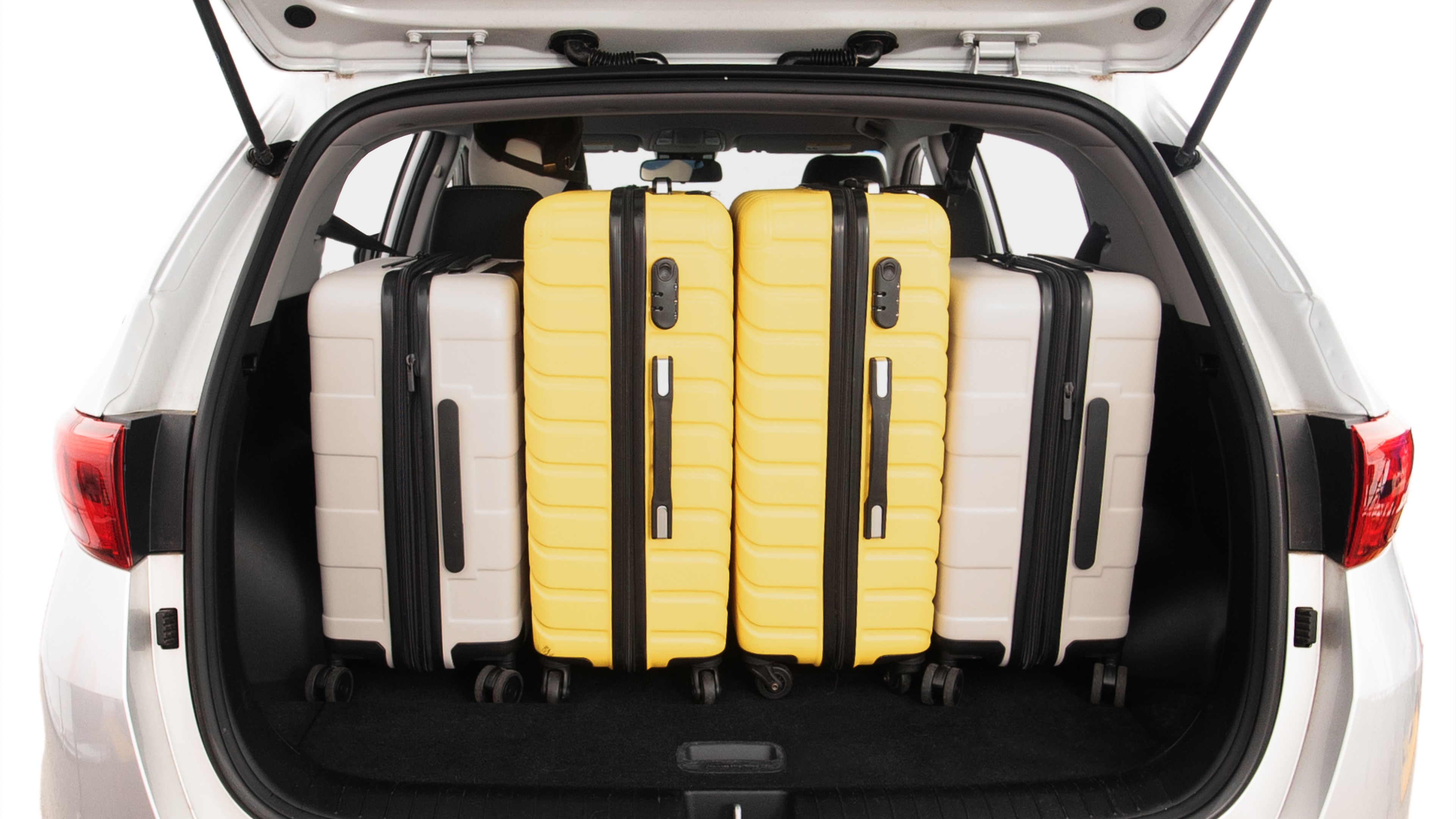 The trunk lid is open, showing full view of the trunk space. Two large and two small suitcases are placed inside.