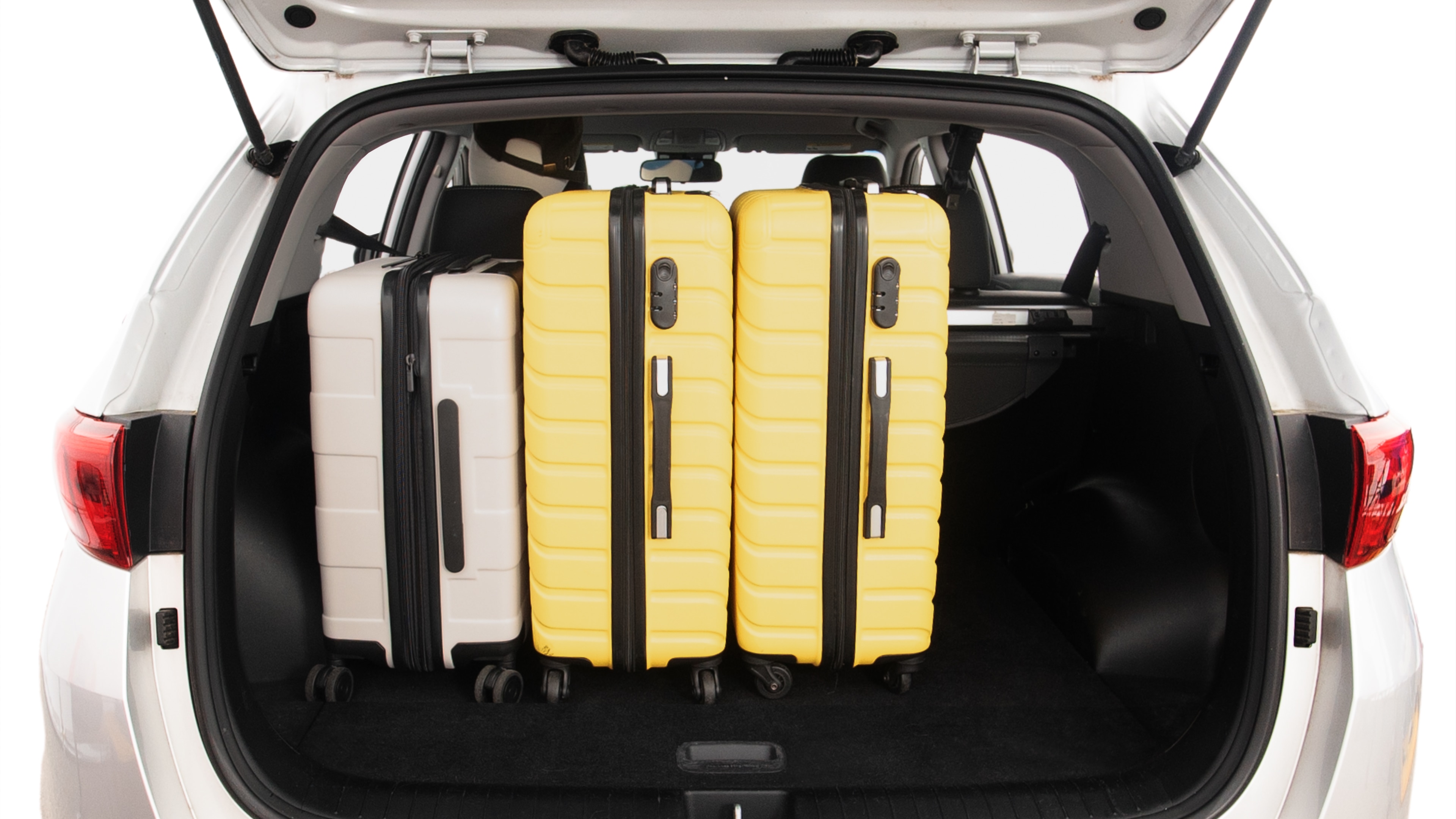 The trunk lid is open, showing full view of the trunk space. Two large and two small suitcases are placed inside.