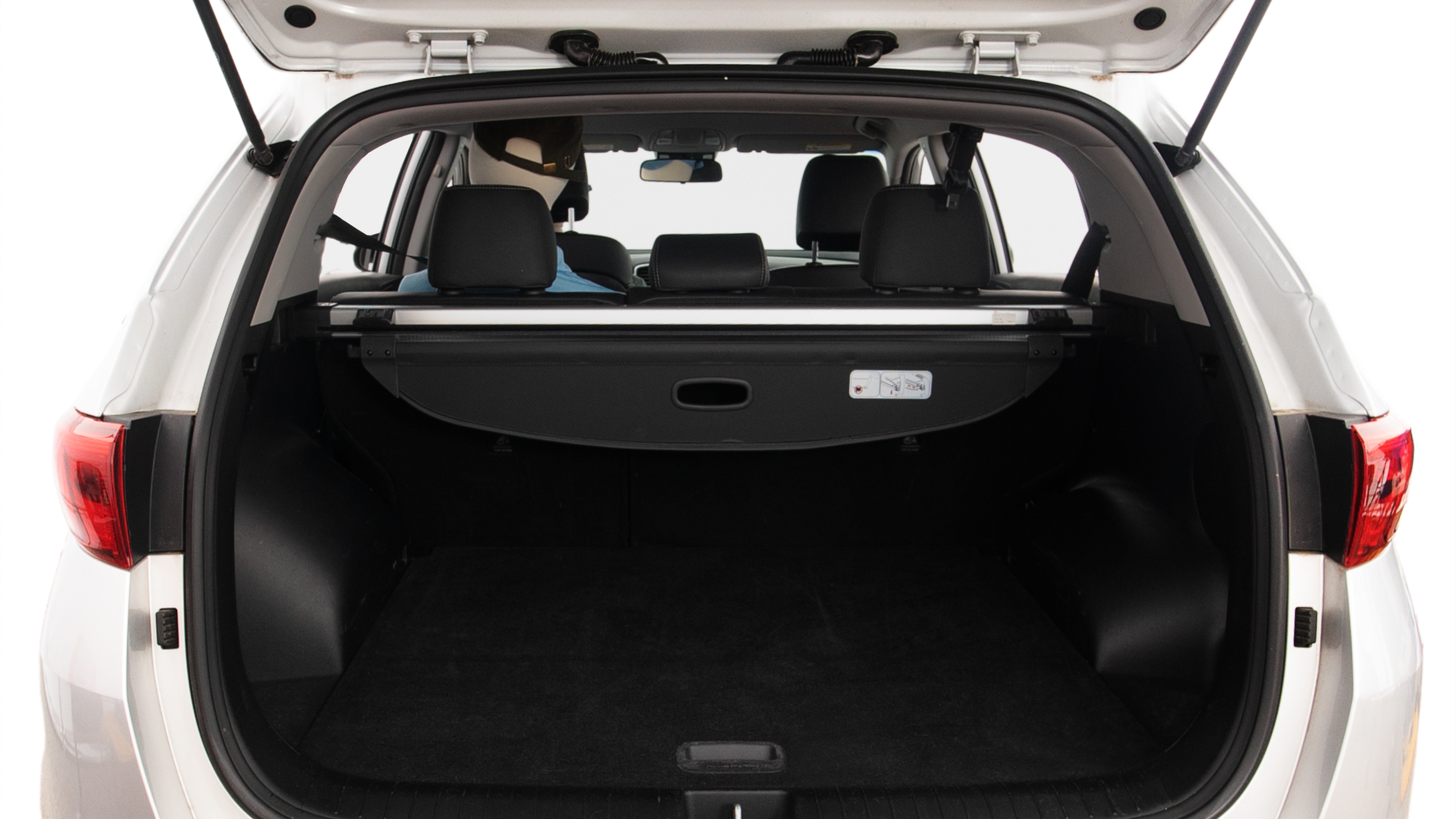 The trunk lid is open, showing full view of the trunk space. Two large and two small suitcases are placed inside.