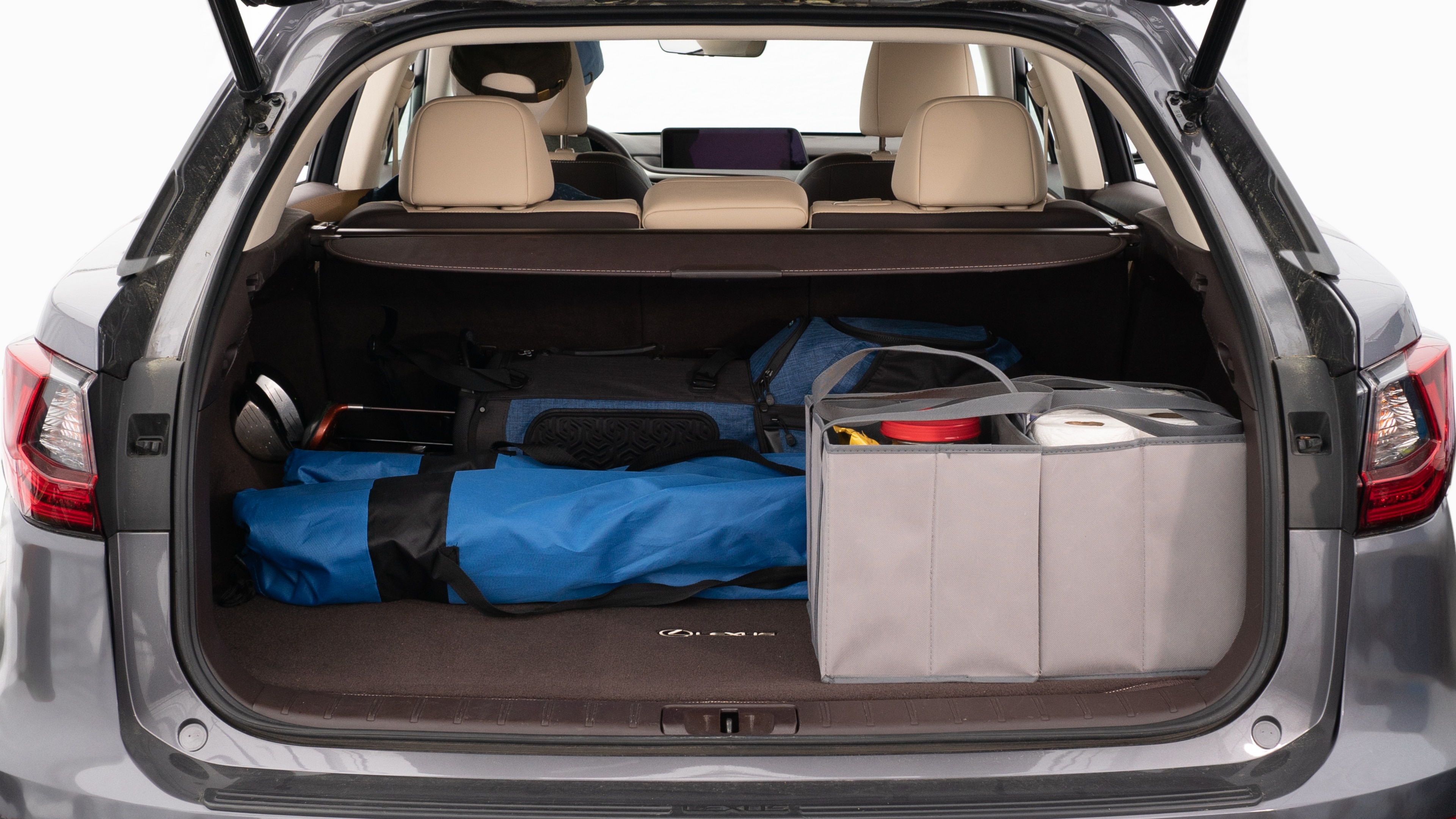 The trunk lid is open showing full view of the trunk. A baby stroller, three grocery carriers, two camping chairs in the carrying bag, and a set of golf clubs are placed inside.