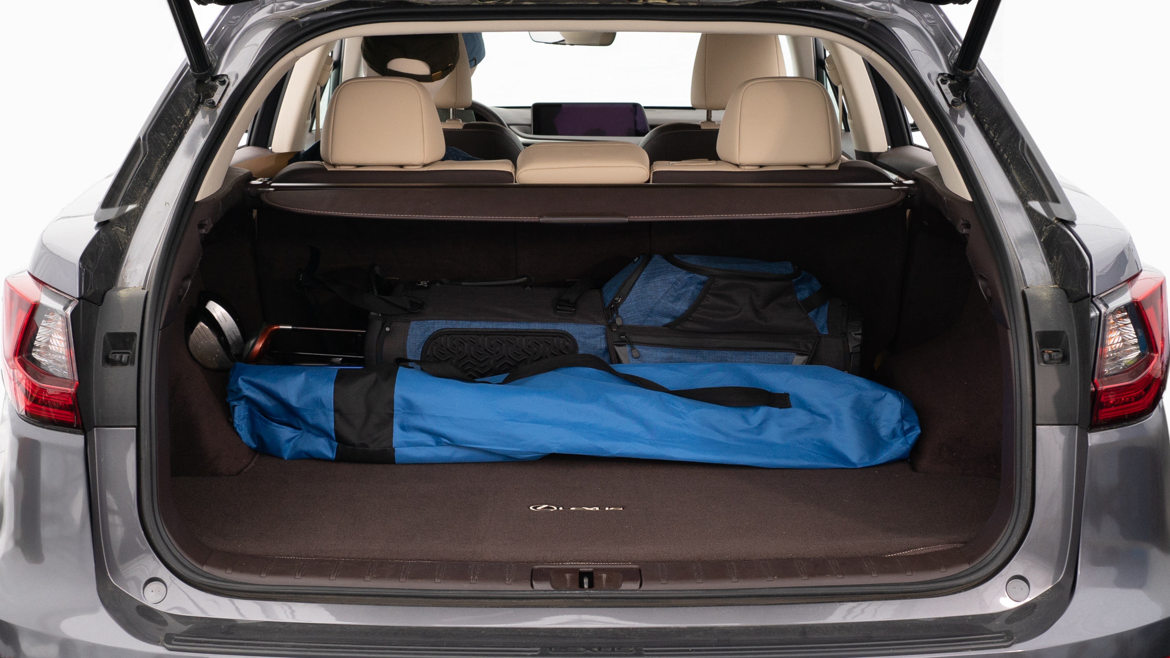 The trunk lid is open showing full view of the trunk. A baby stroller, three grocery carriers, two camping chairs in the carrying bag, and a set of golf clubs are placed inside.