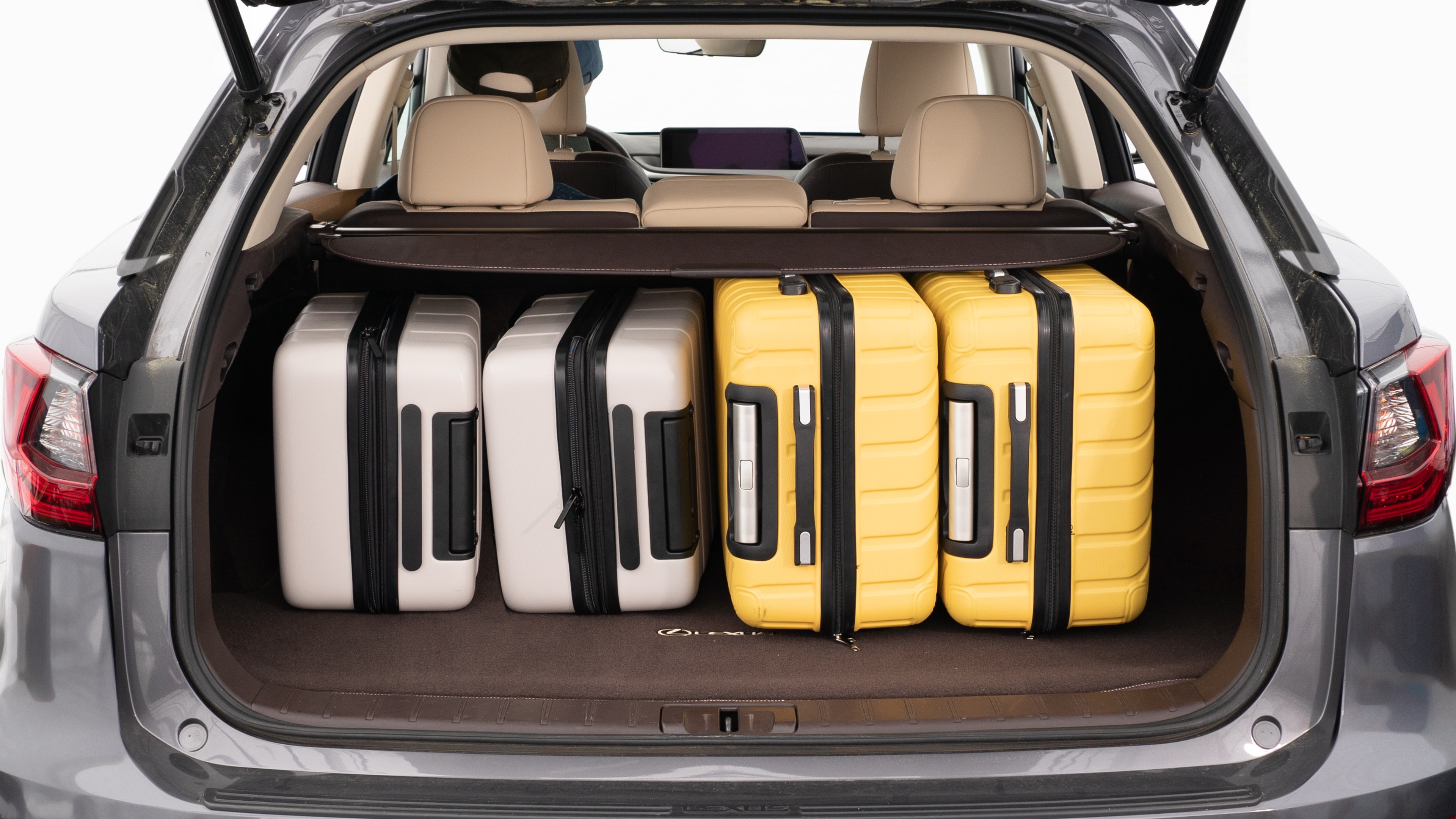 The trunk lid is open, showing a full view of the trunk space. Two large and two small suitcases are are placed inside.