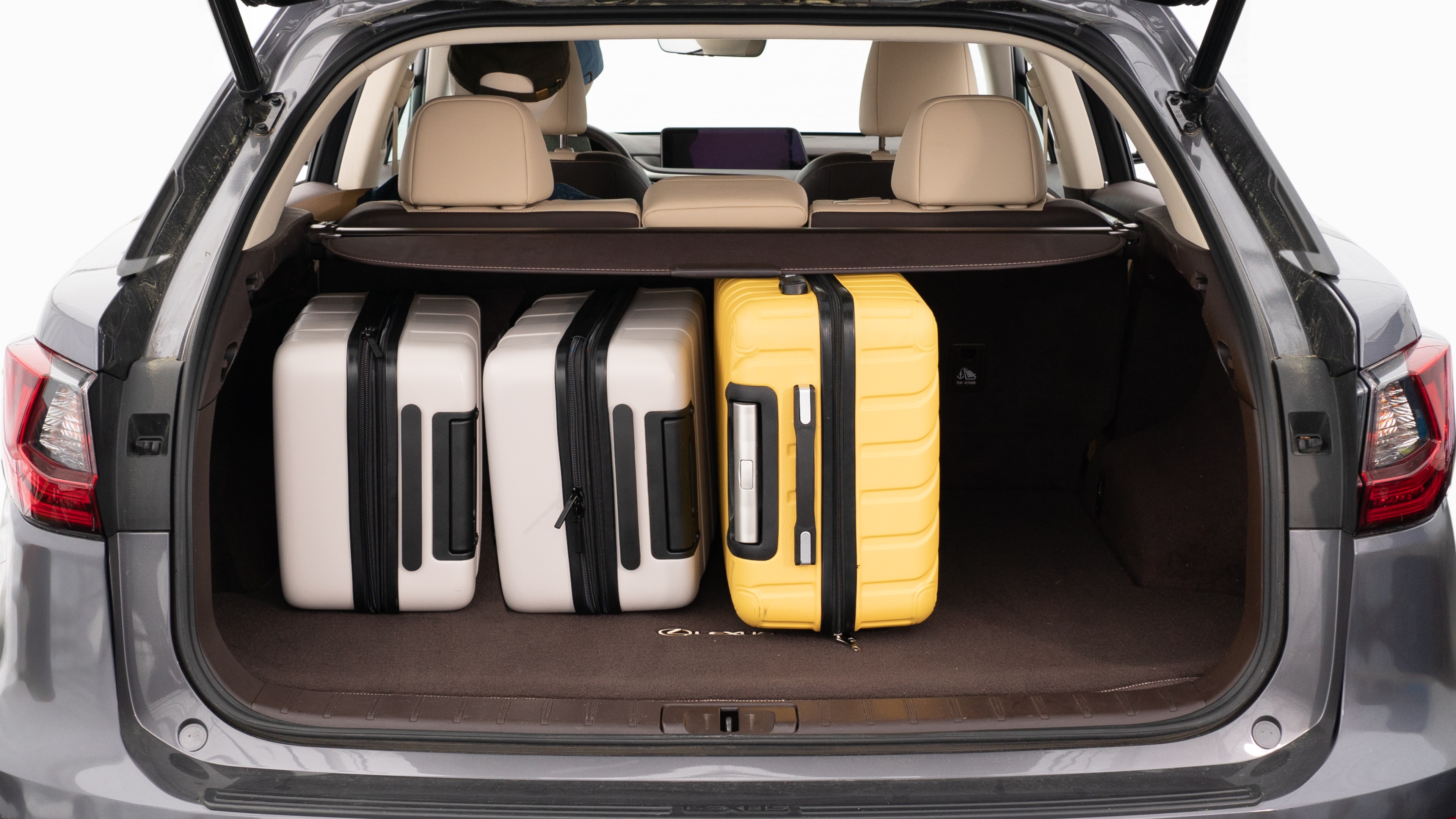 The trunk lid is open, showing a full view of the trunk space. Two large and two small suitcases are are placed inside.
