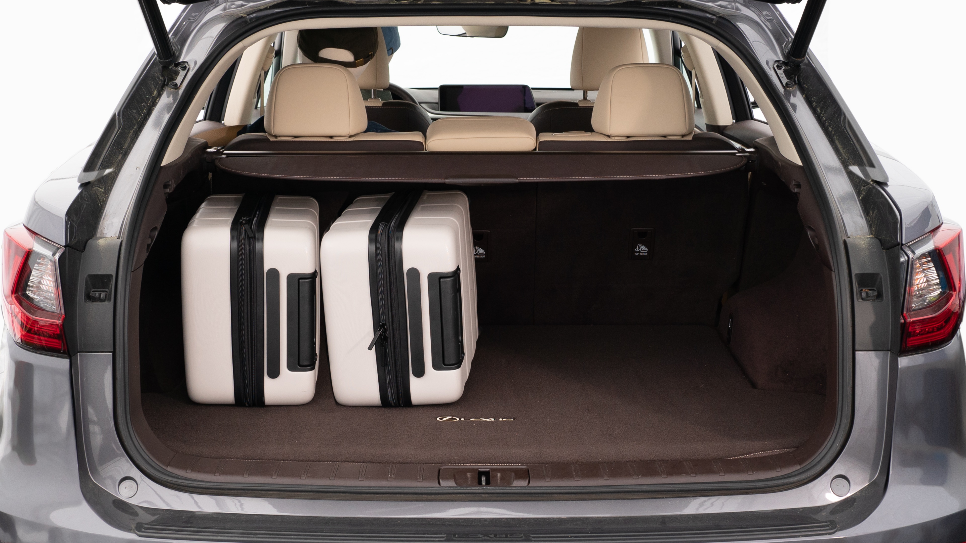 The trunk lid is open, showing a full view of the trunk space. Two large and two small suitcases are are placed inside.
