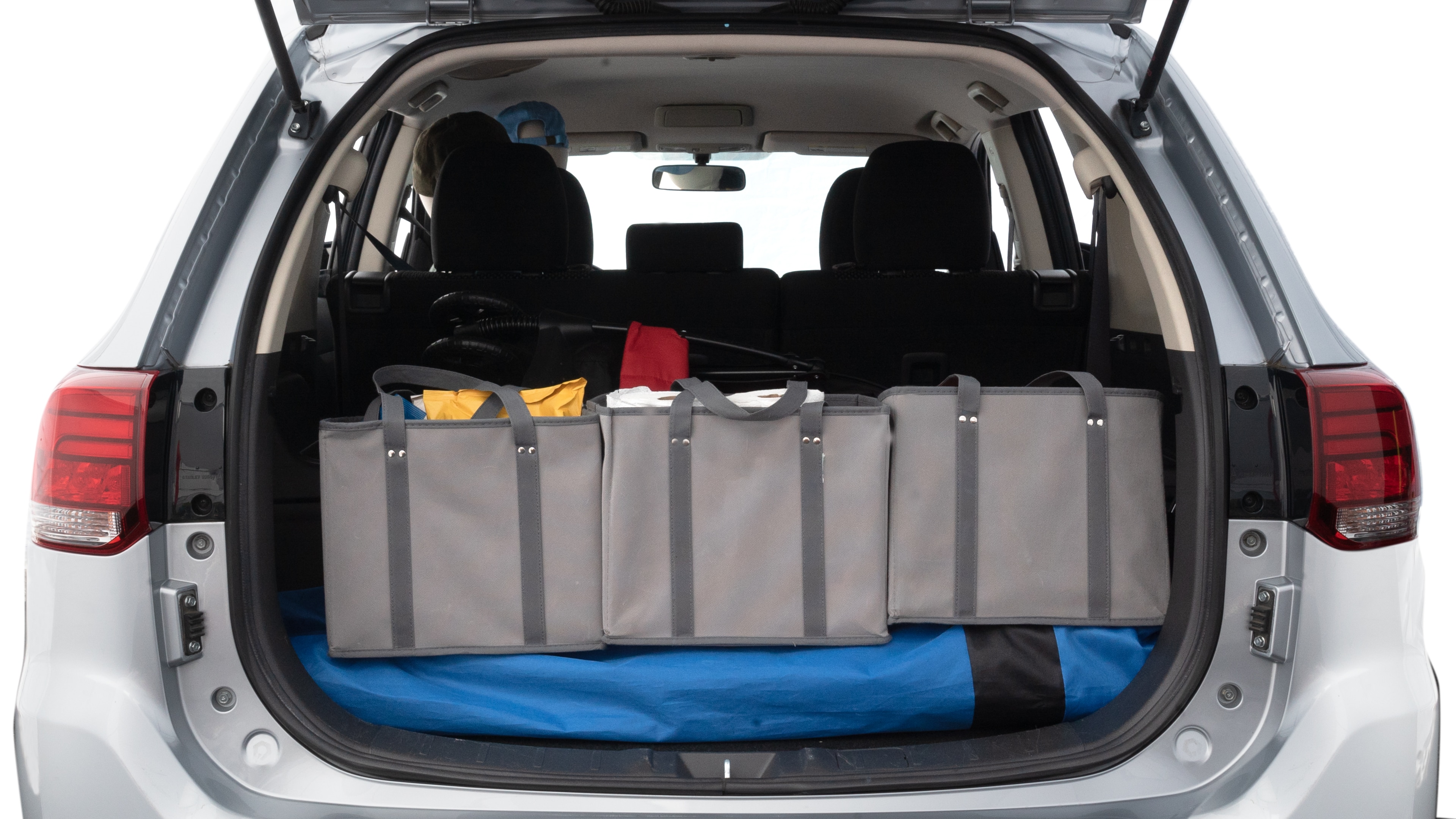 The trunk lid is open showing full view of the trunk. A baby stroller, three grocery carriers, two camping chairs in the carrying bag, and a set of golf clubs are placed inside.