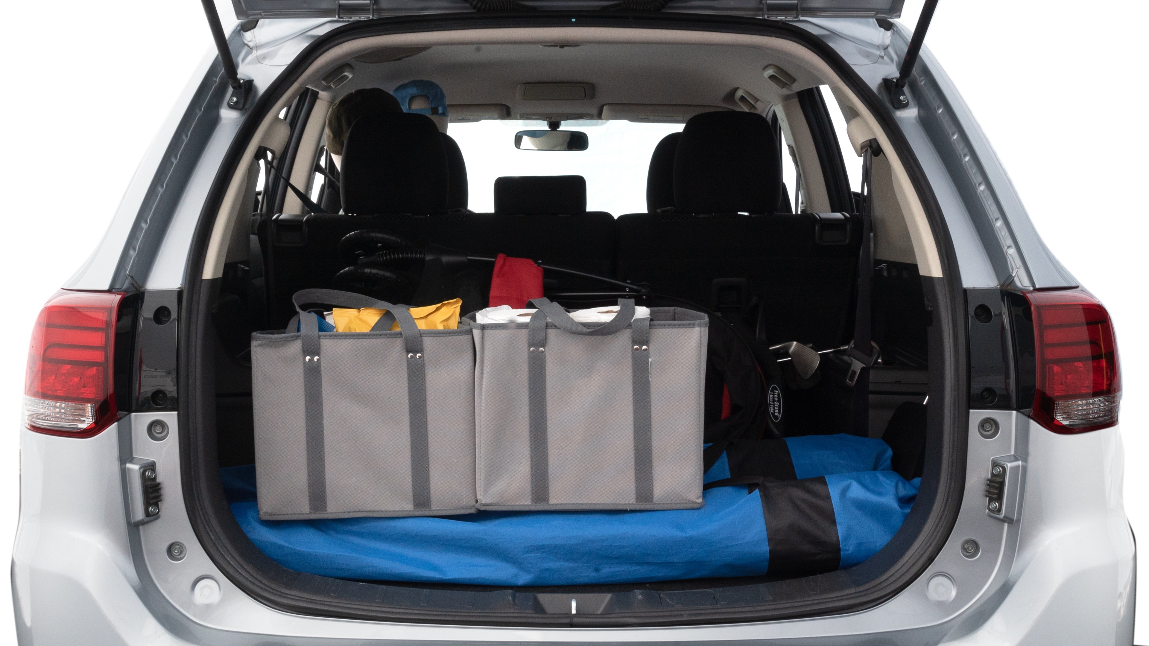 The trunk lid is open showing full view of the trunk. A baby stroller, three grocery carriers, two camping chairs in the carrying bag, and a set of golf clubs are placed inside.