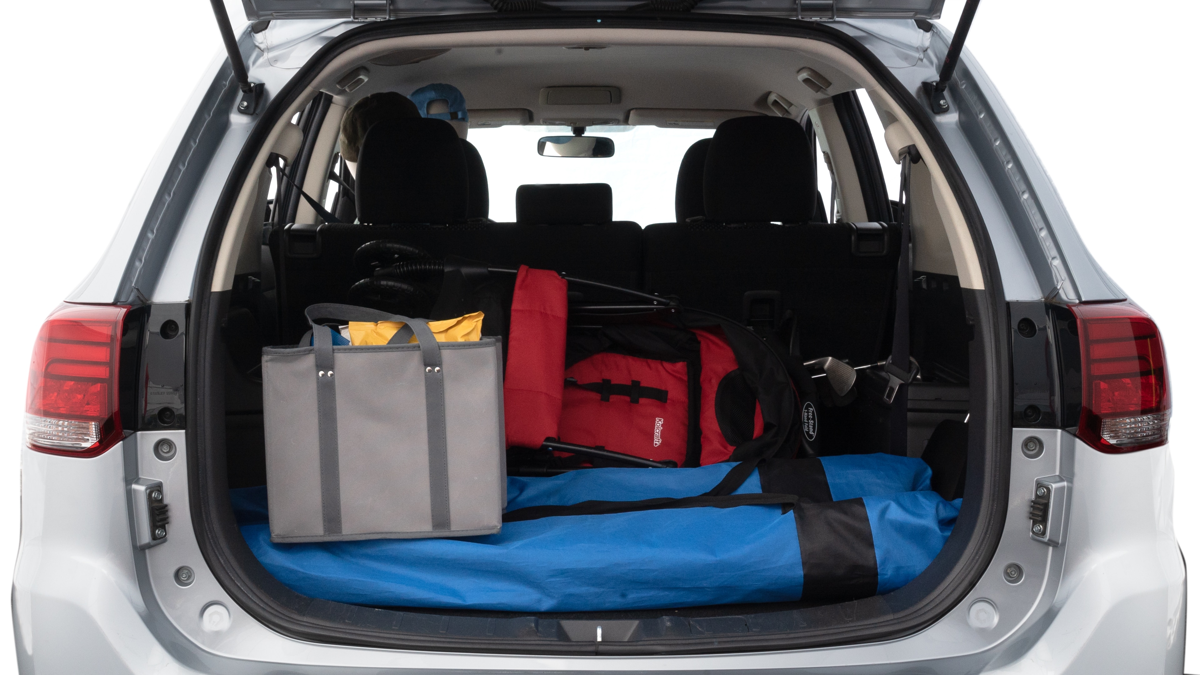 The trunk lid is open showing full view of the trunk. A baby stroller, three grocery carriers, two camping chairs in the carrying bag, and a set of golf clubs are placed inside.