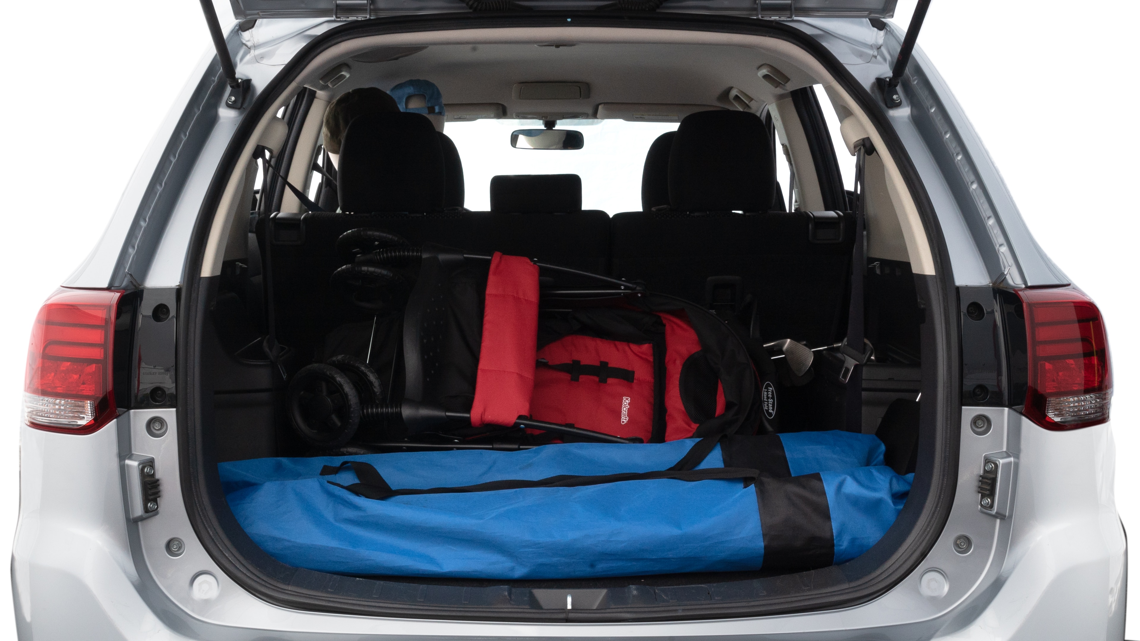 The trunk lid is open showing full view of the trunk. A baby stroller, three grocery carriers, two camping chairs in the carrying bag, and a set of golf clubs are placed inside.