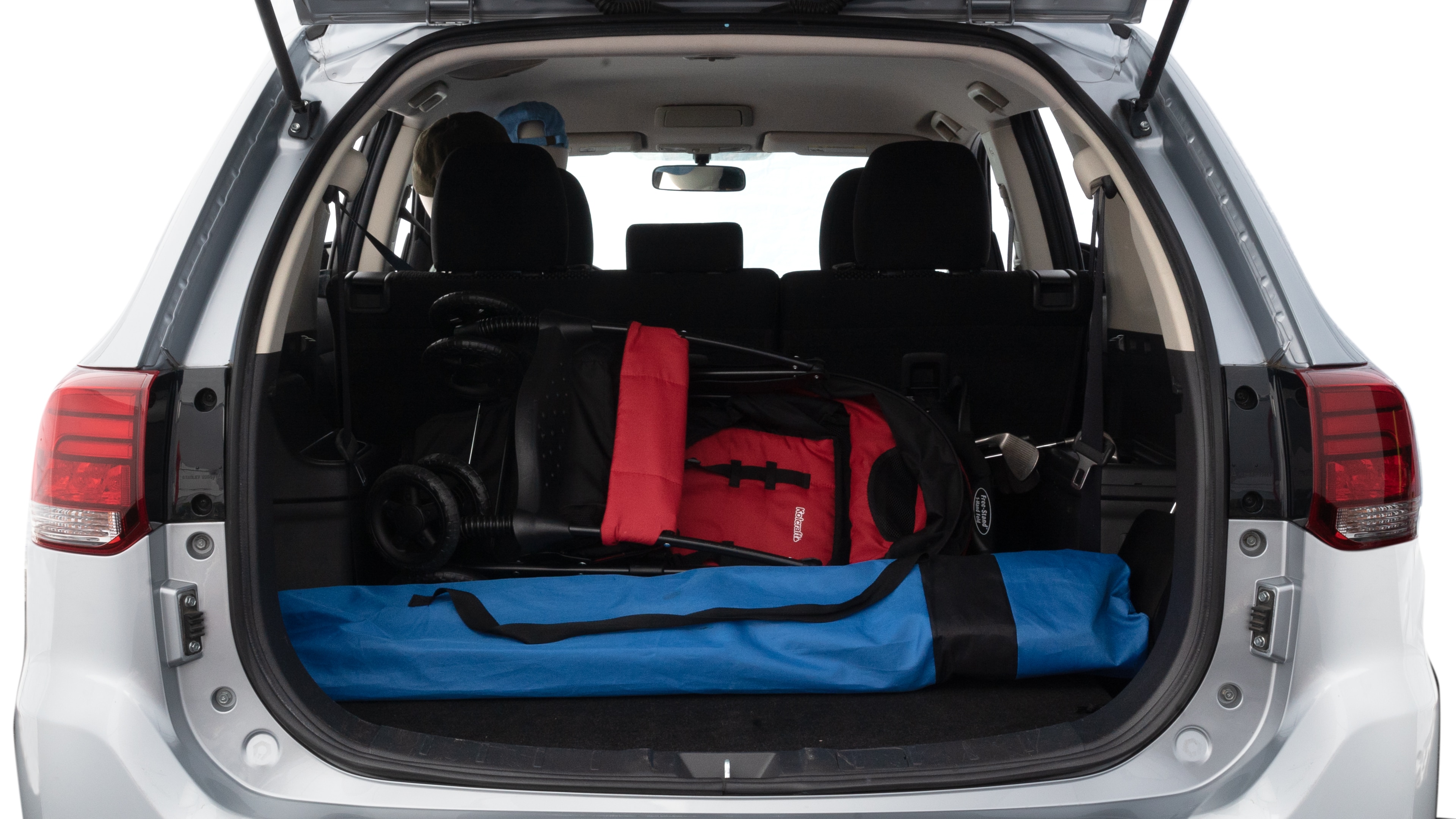 The trunk lid is open showing full view of the trunk. A baby stroller, three grocery carriers, two camping chairs in the carrying bag, and a set of golf clubs are placed inside.