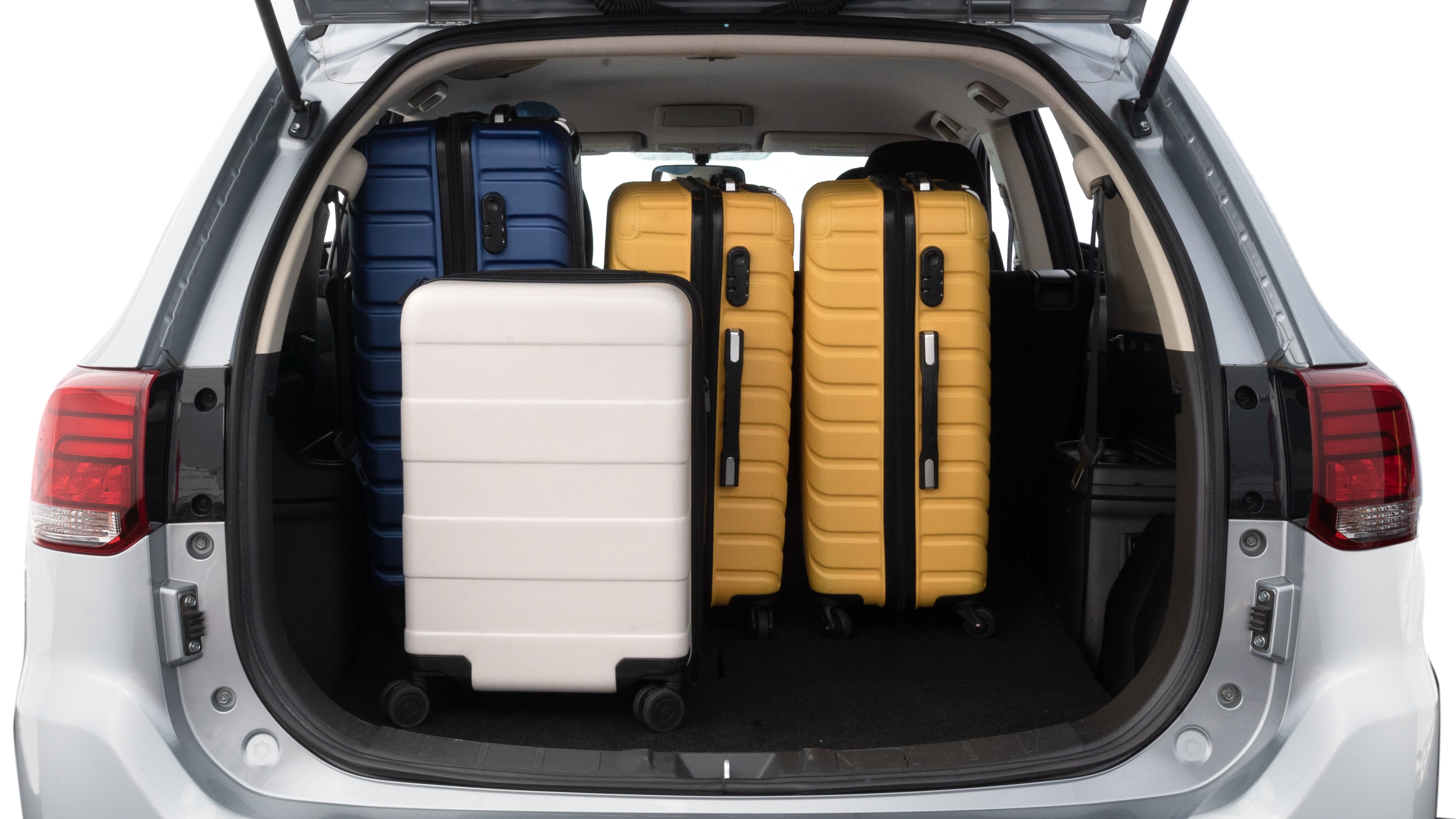 The trunk lid is open, showing full view of the trunk space. One large, two medium, and two small suitcases are placed inside.