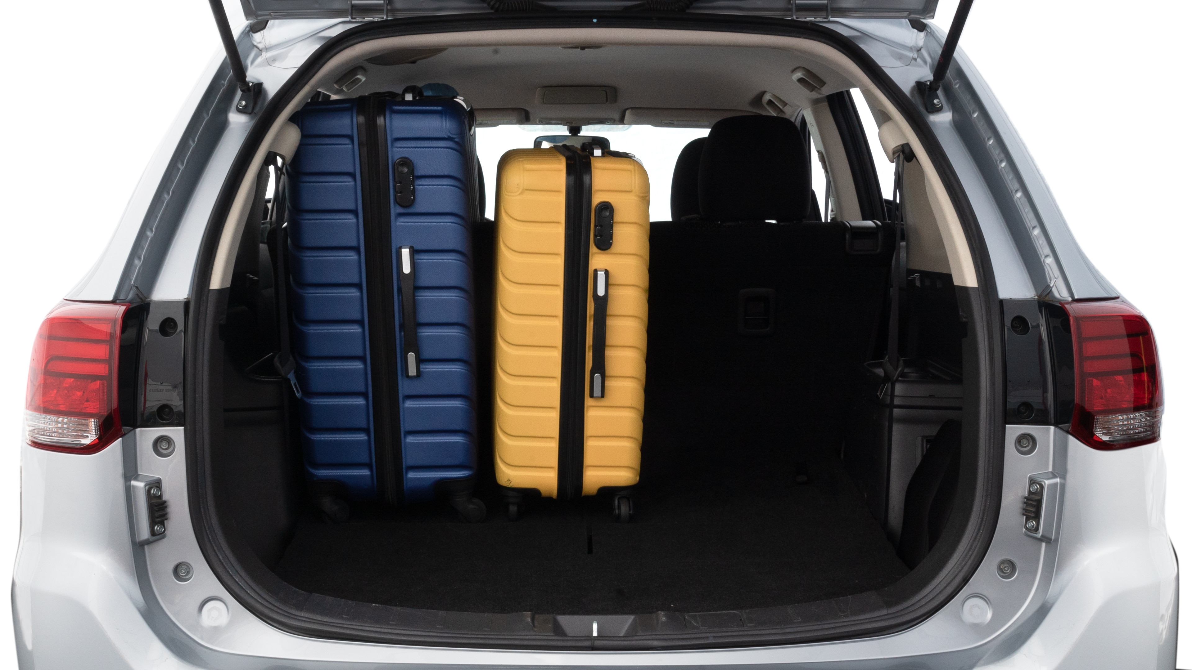 The trunk lid is open, showing full view of the trunk space. One large, two medium, and two small suitcases are placed inside.