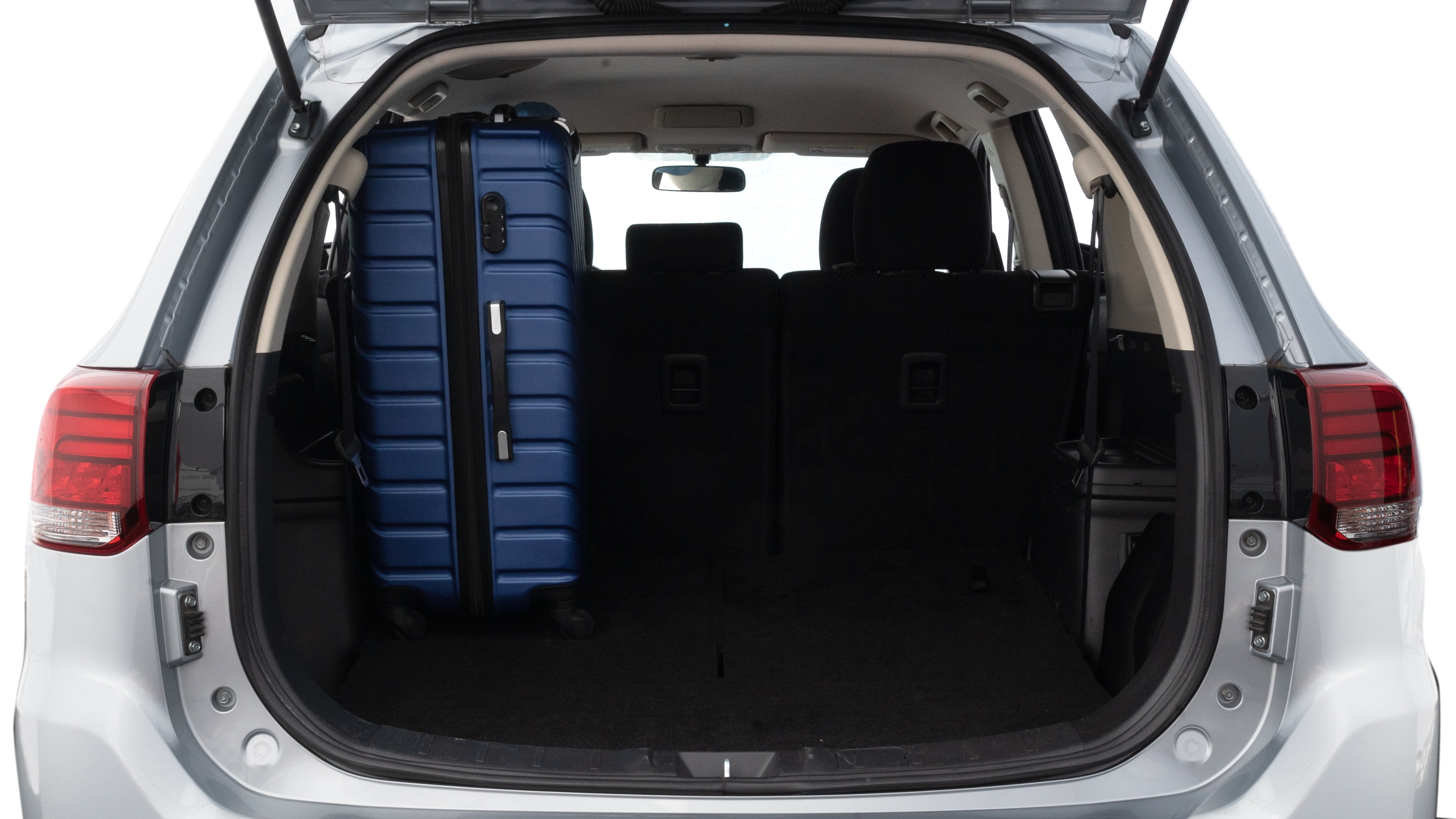 The trunk lid is open, showing full view of the trunk space. One large, two medium, and two small suitcases are placed inside.