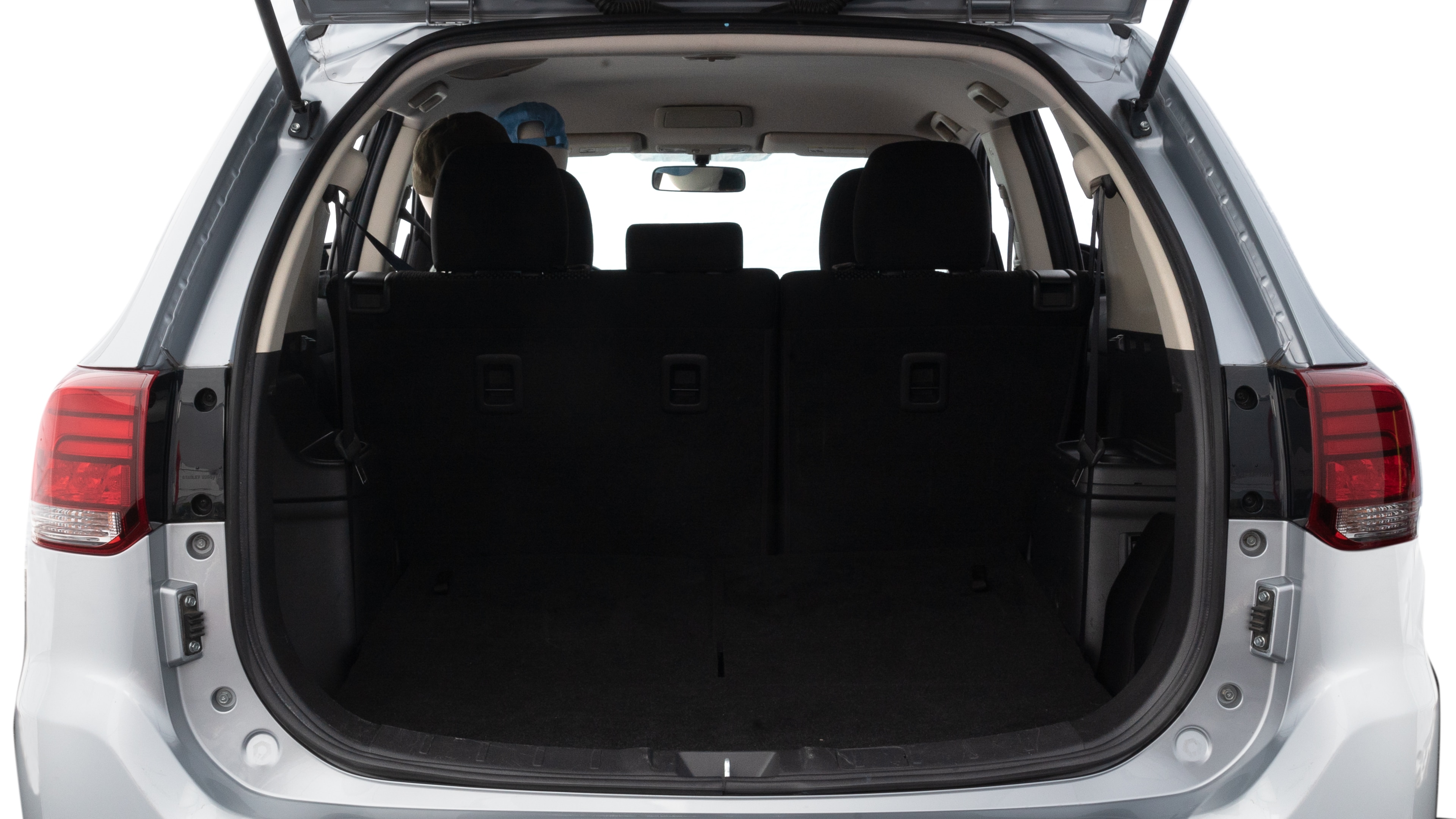 The trunk lid is open, showing full view of the trunk space. One large, two medium, and two small suitcases are placed inside.
