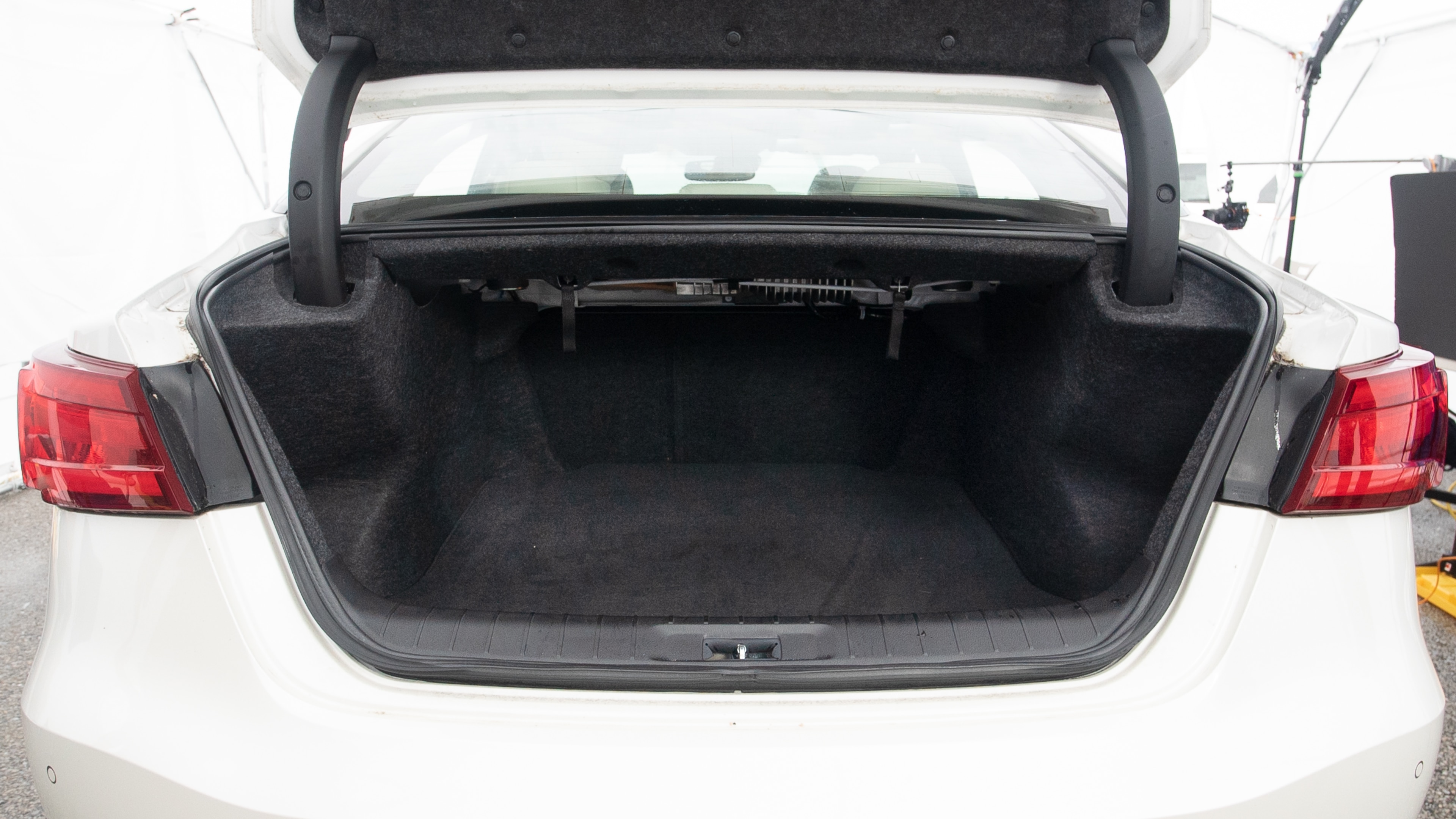 The trunk lid is open showing full view of the trunk. A baby stroller, three grocery carriers, one camping chairs in the carrying bag, and a set of golf clubs are placed inside.