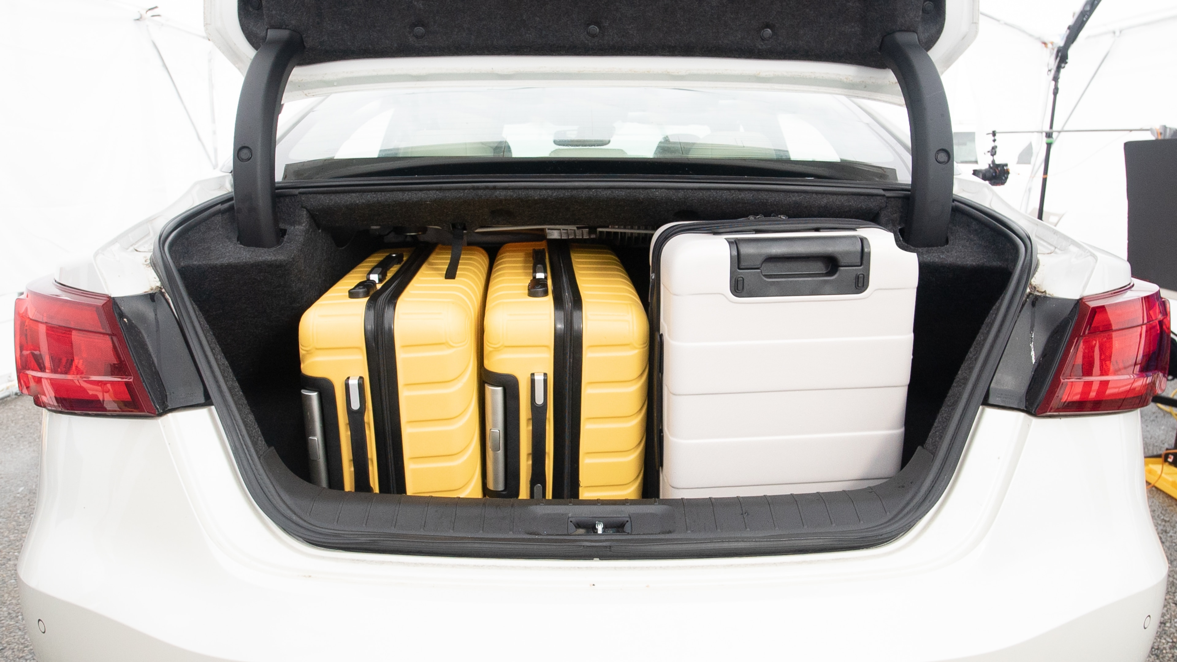 The trunk lid is open, showing full view of the trunk space. Two large and two small suitcases are placed inside.