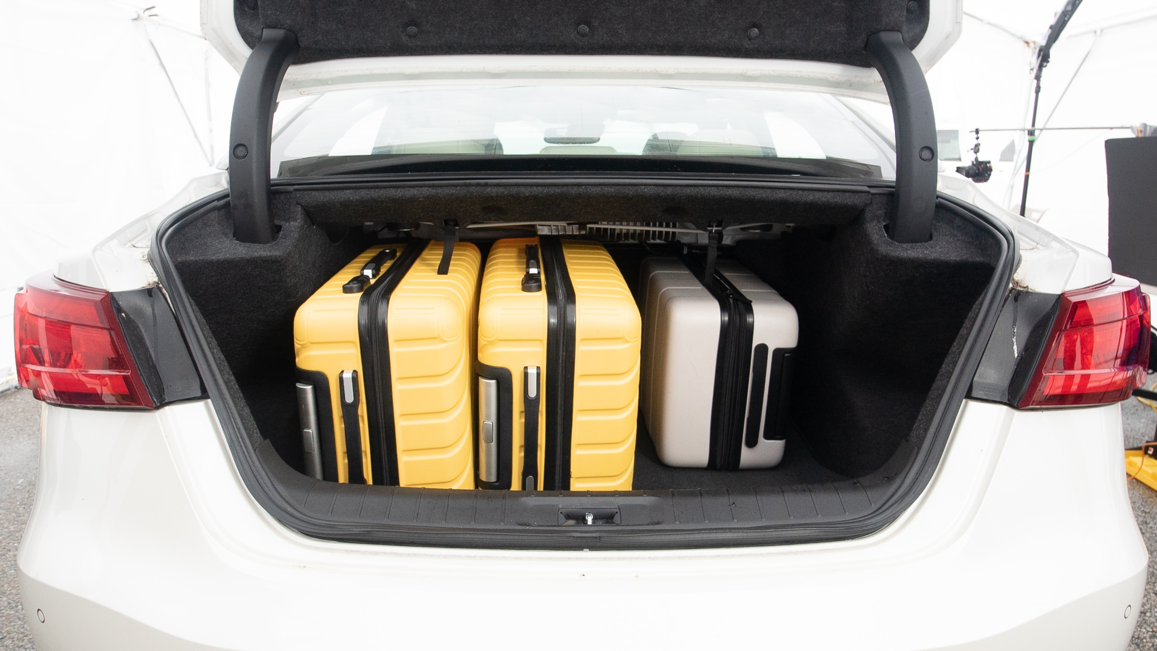 The trunk lid is open, showing full view of the trunk space. Two large and two small suitcases are placed inside.