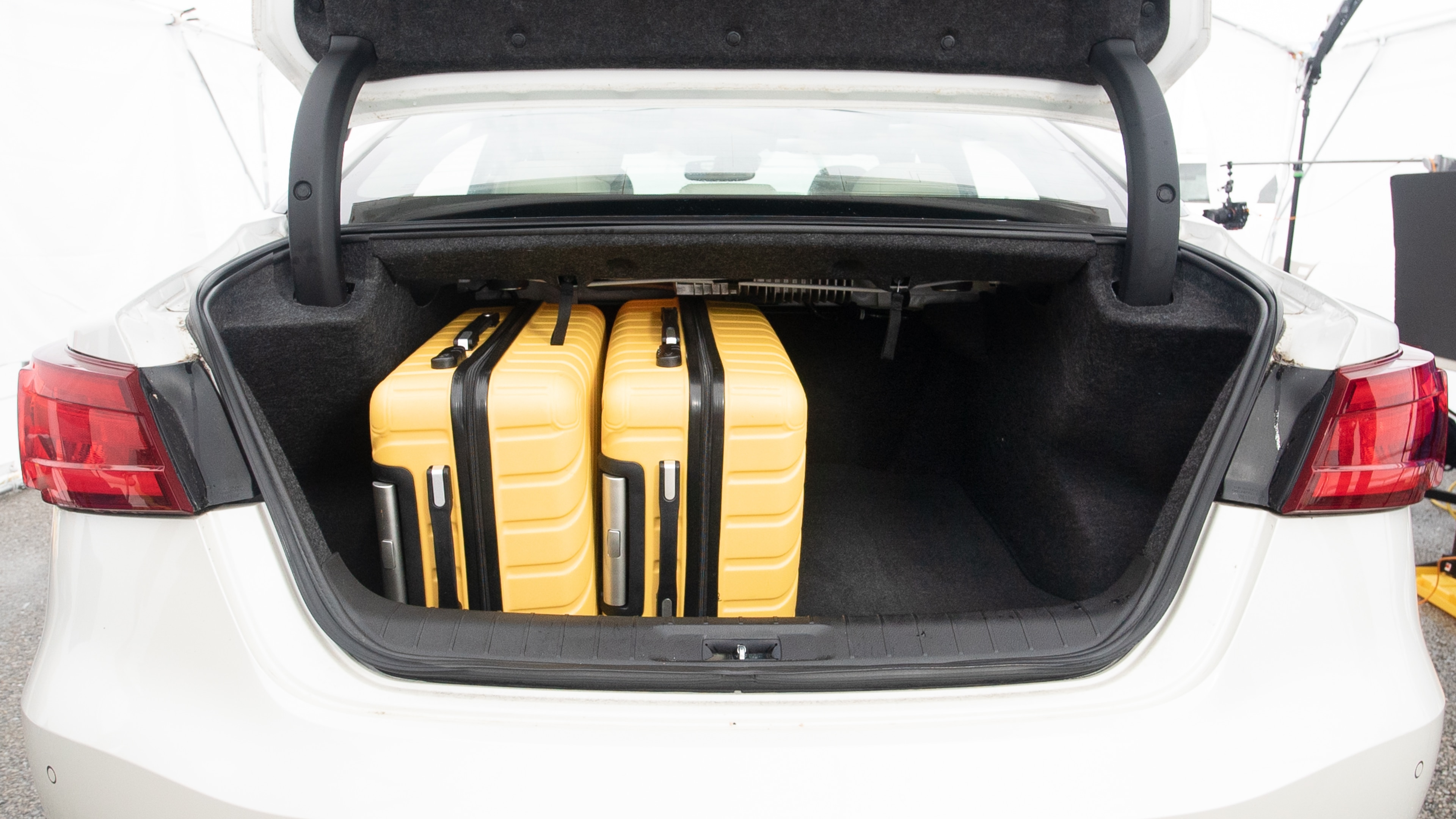 The trunk lid is open, showing full view of the trunk space. Two large and two small suitcases are placed inside.