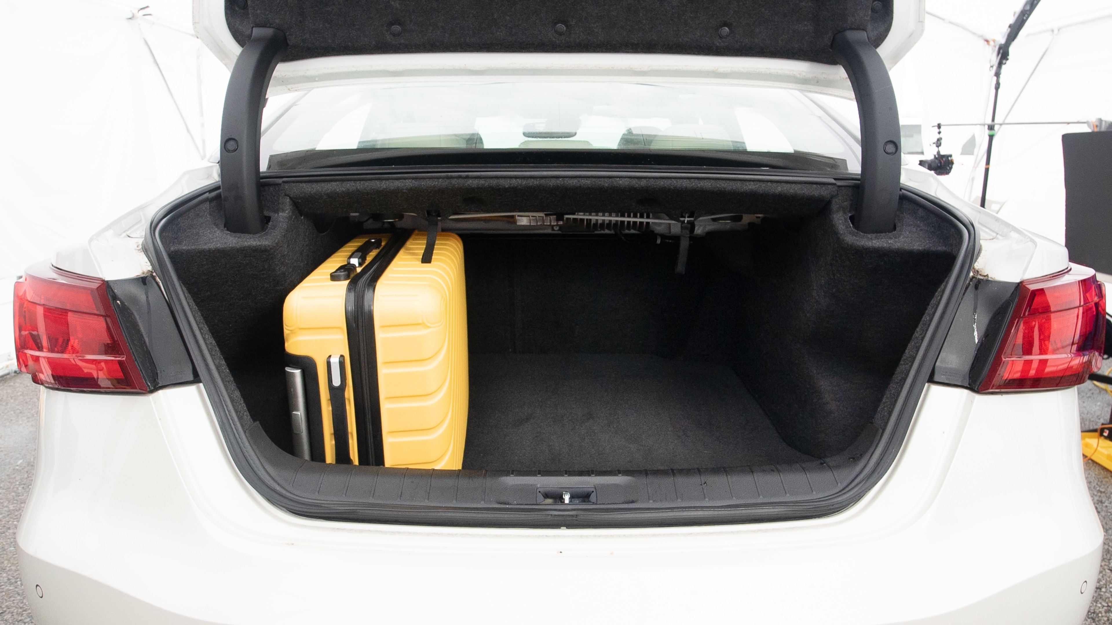 The trunk lid is open, showing full view of the trunk space. Two large and two small suitcases are placed inside.